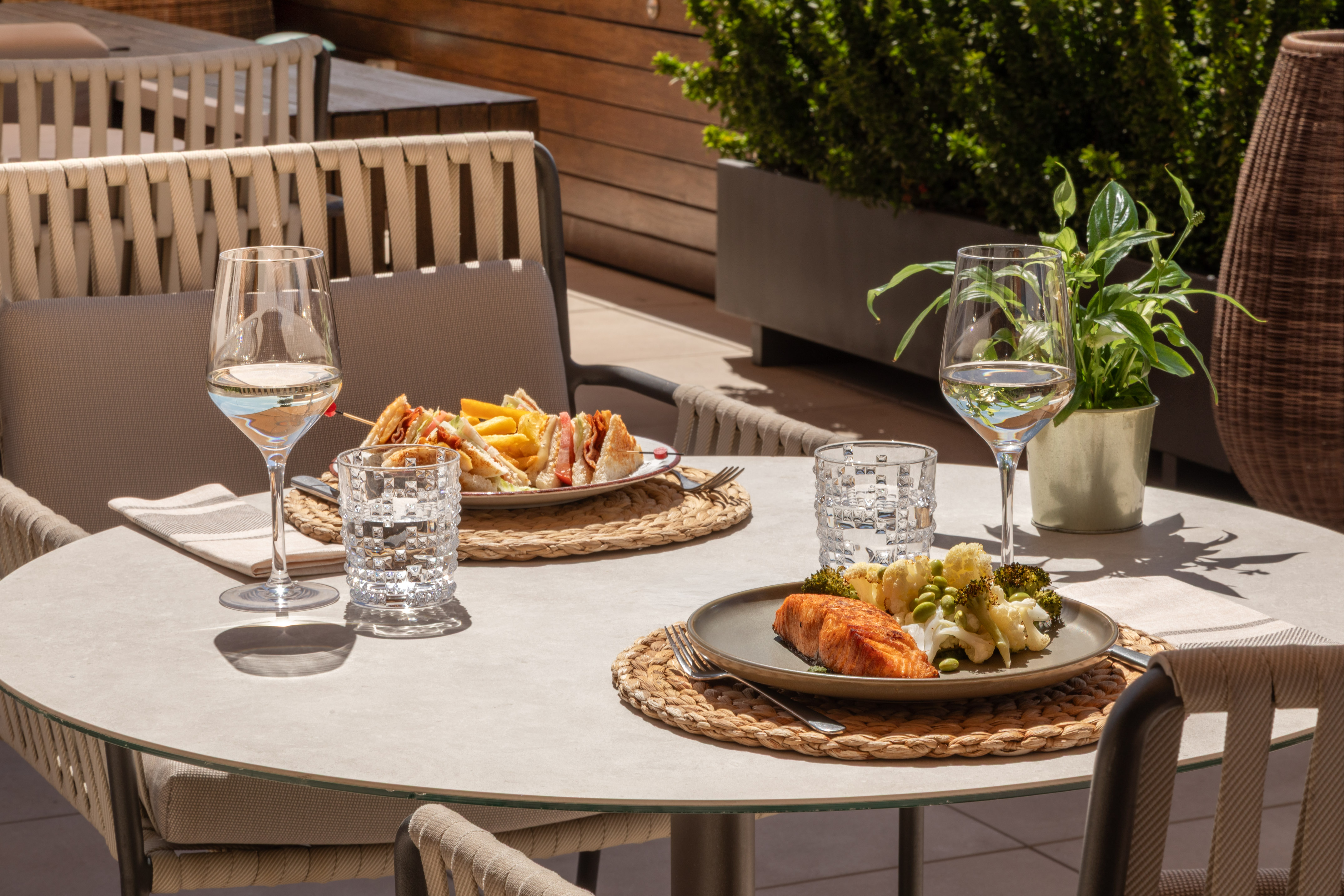 Outdoor dining: grilled salmon, club sandwich, white wine on a terrace.
