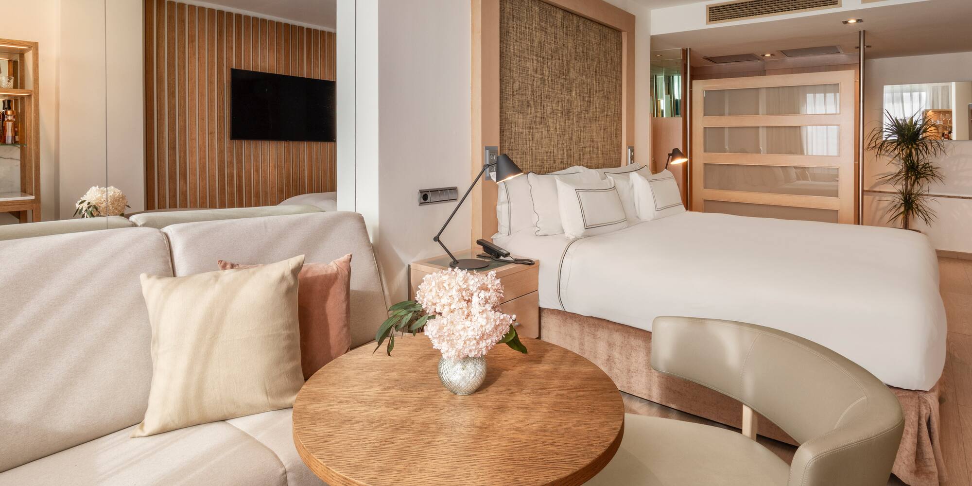 Modern hotel suite with clean design, king bed, and light wood furnishings.