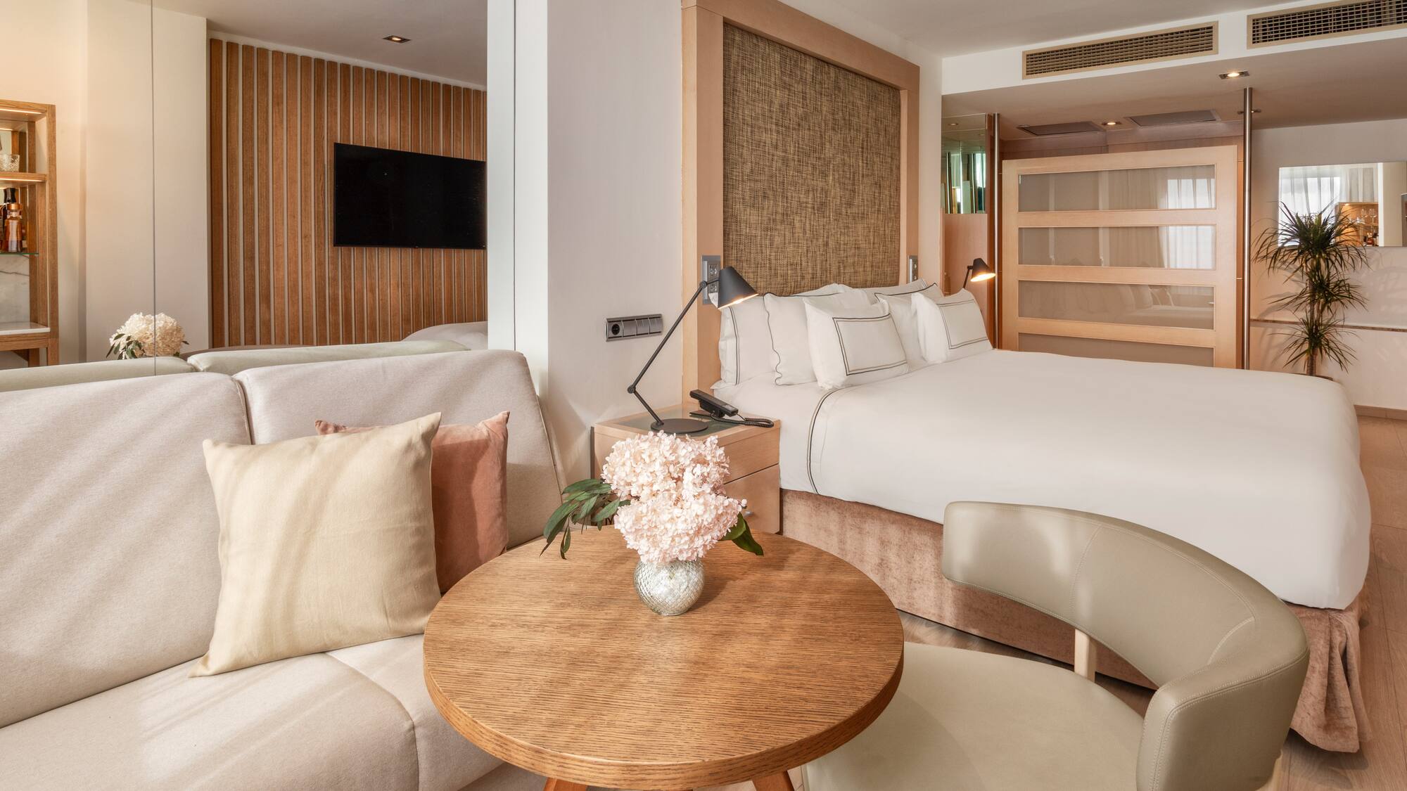 Modern hotel suite with clean design, king bed, and light wood furnishings.