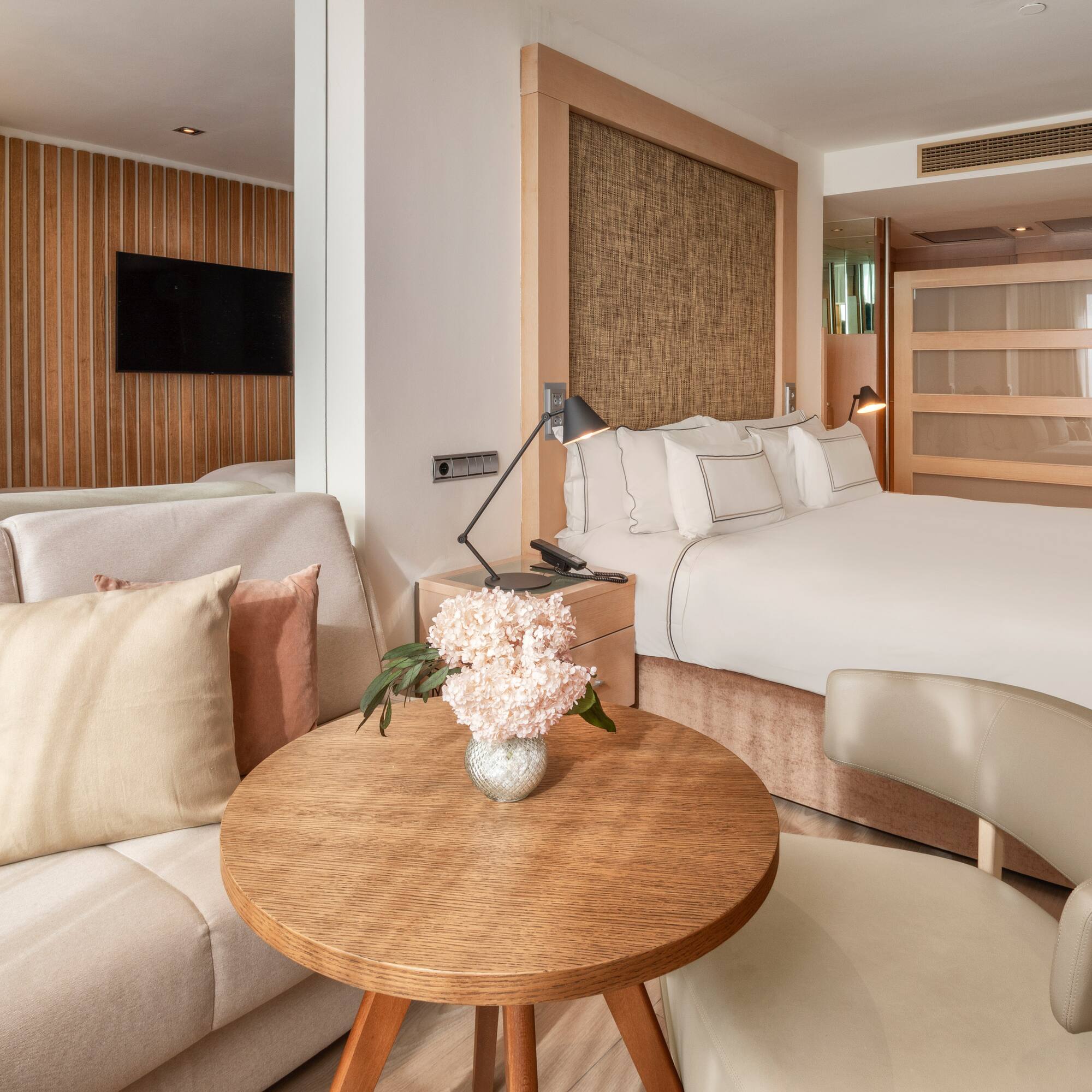 Modern hotel suite with clean design, king bed, and light wood furnishings.