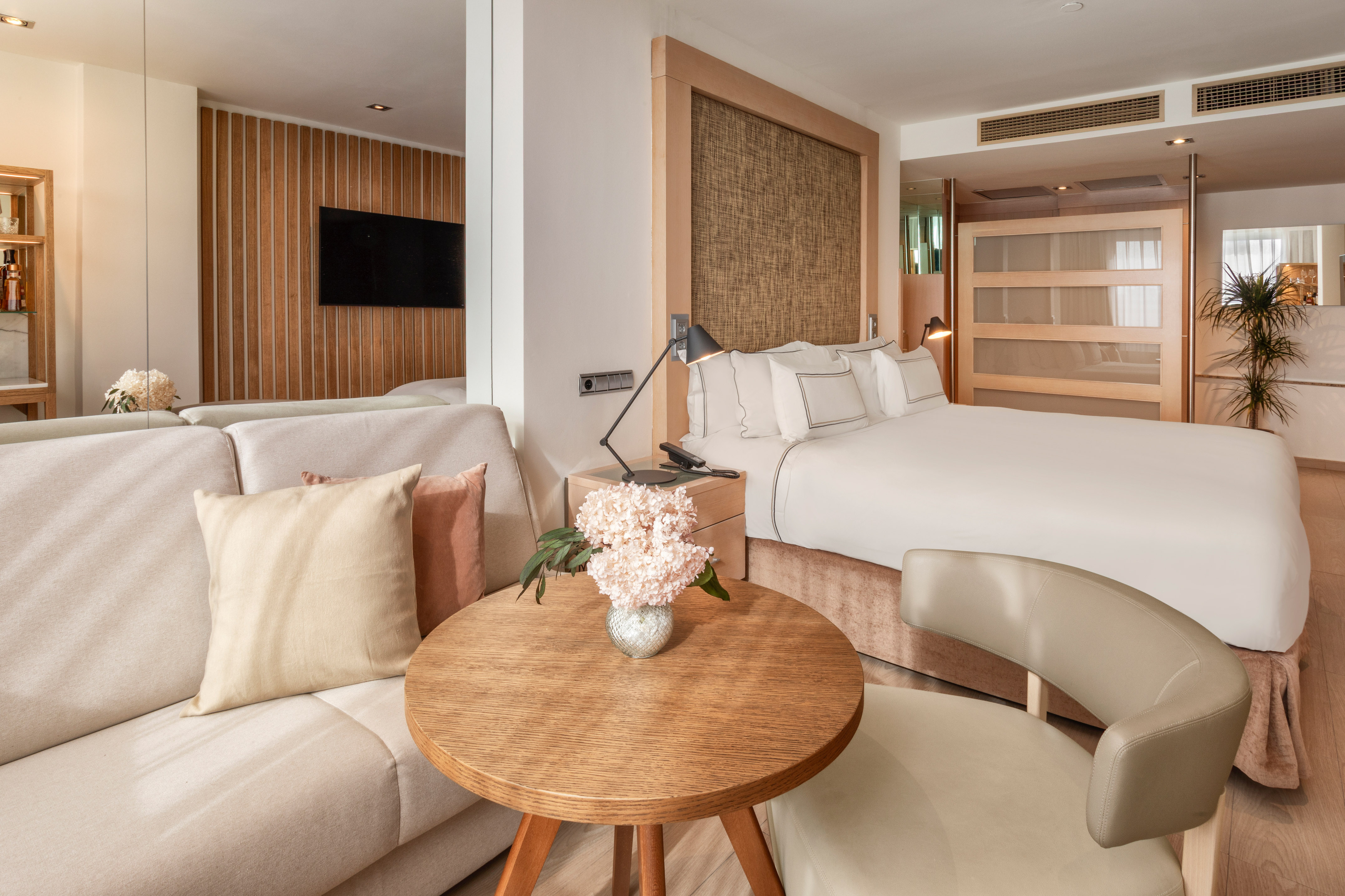 Moderna suite de hotel con cama doble, sofá, mesa de centro y decoración.*