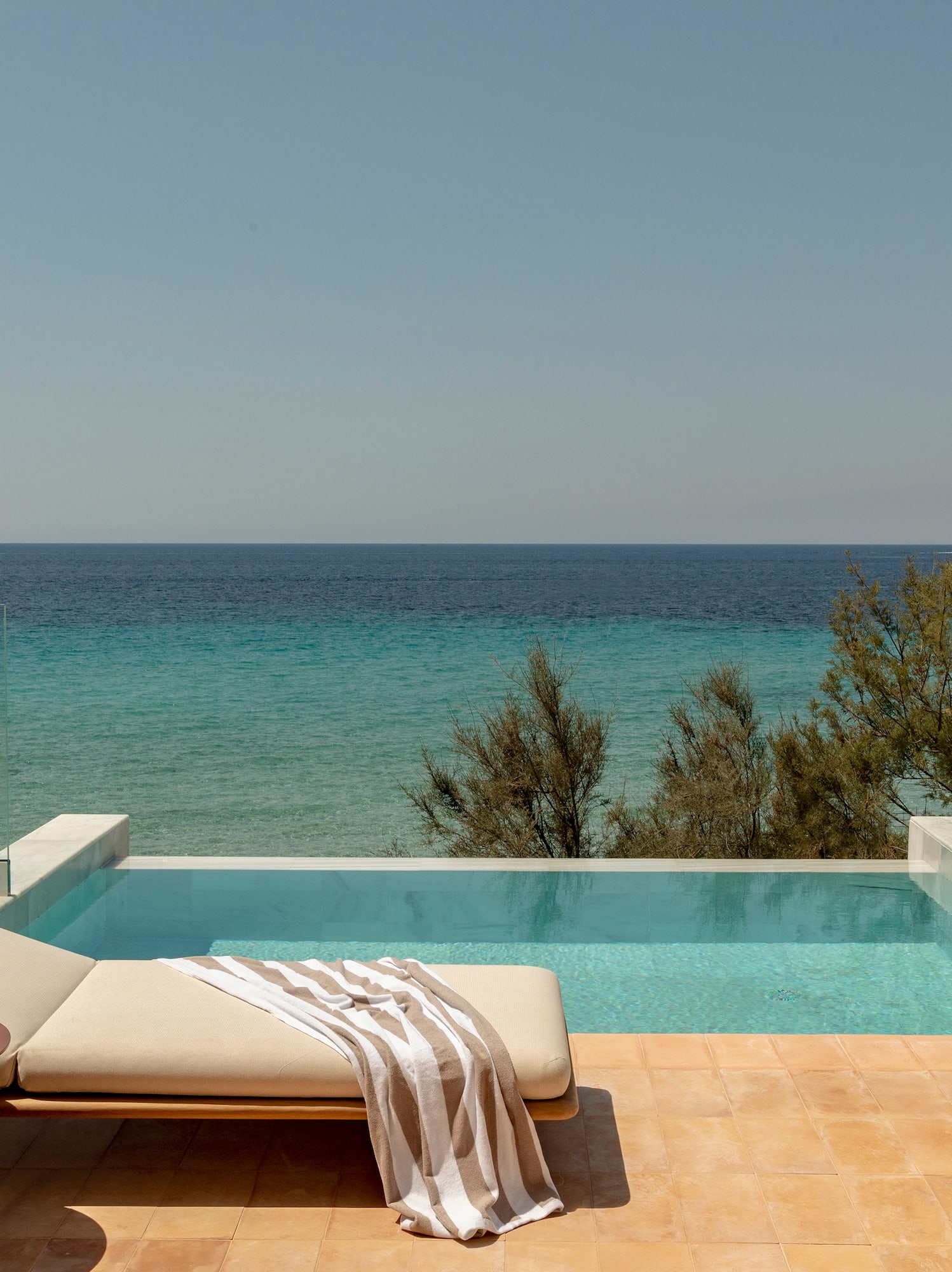 Private infinity pool overlooking the ocean, with sunbed and outdoor shower.