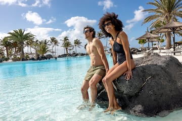 a man and woman sitting on a rock in water