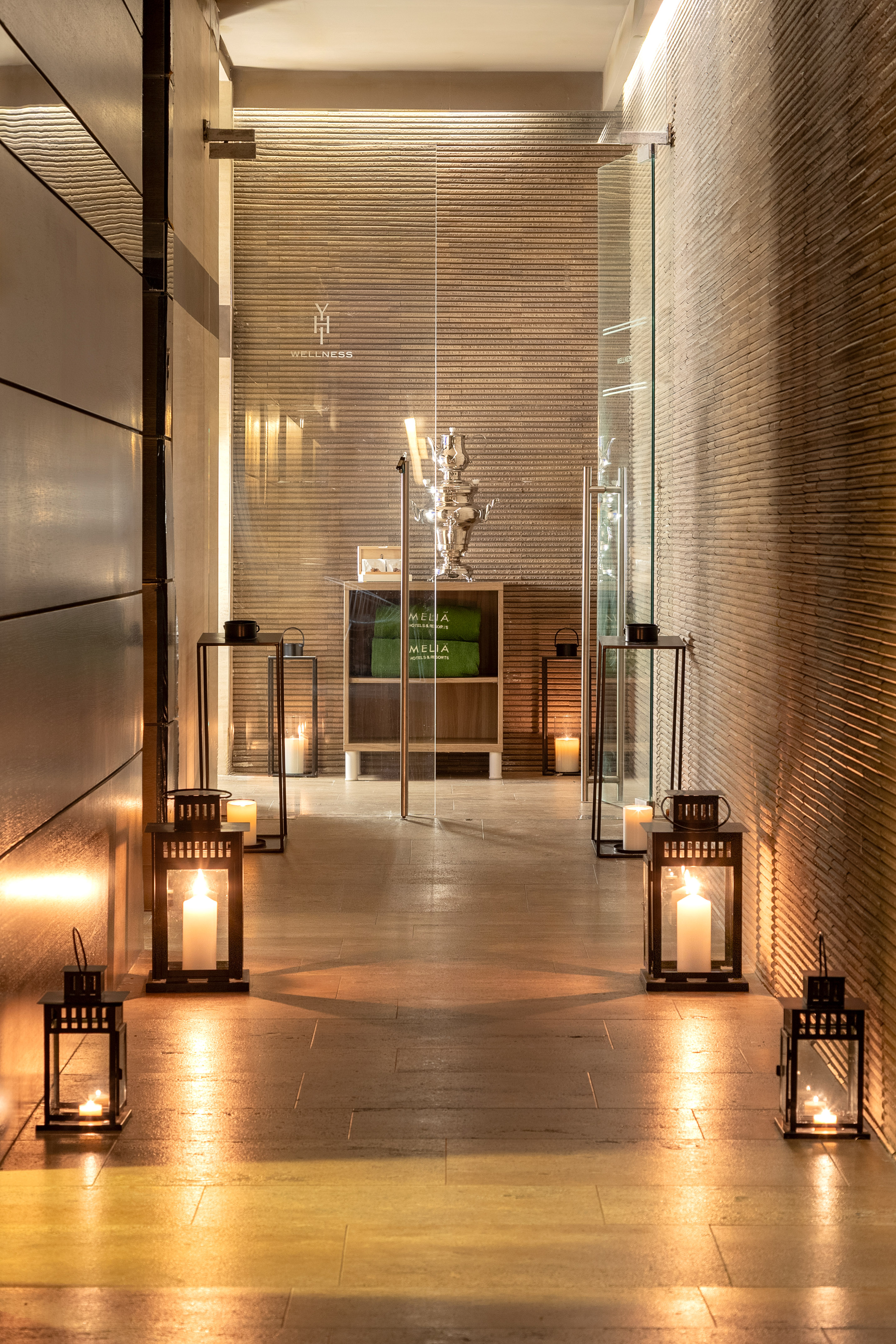 Wellness center entrance with glowing lanterns, textured walls, and glass door.