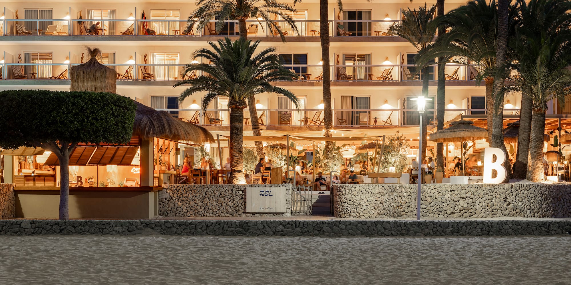 a building with palm trees and people sitting at tables