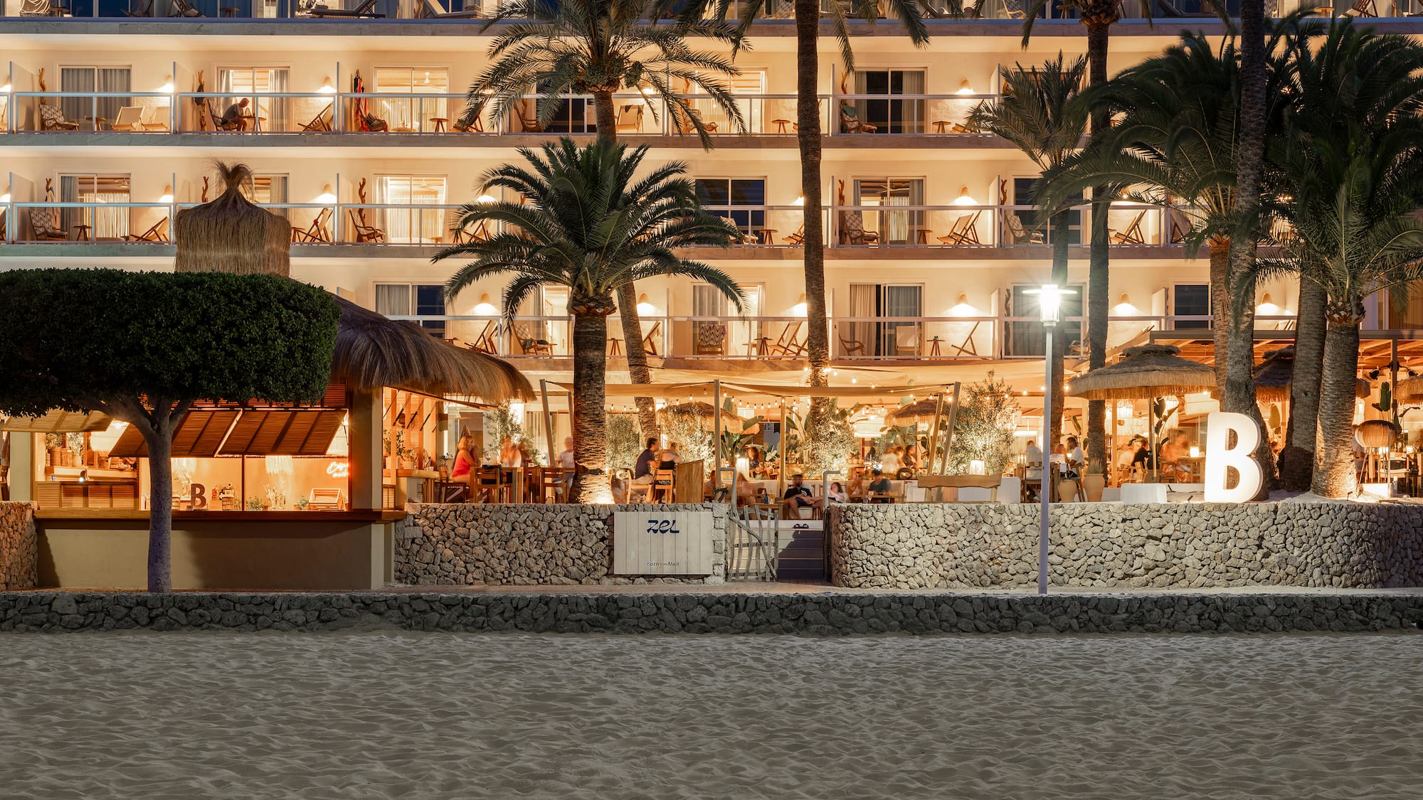 a building with palm trees and people sitting at tables
