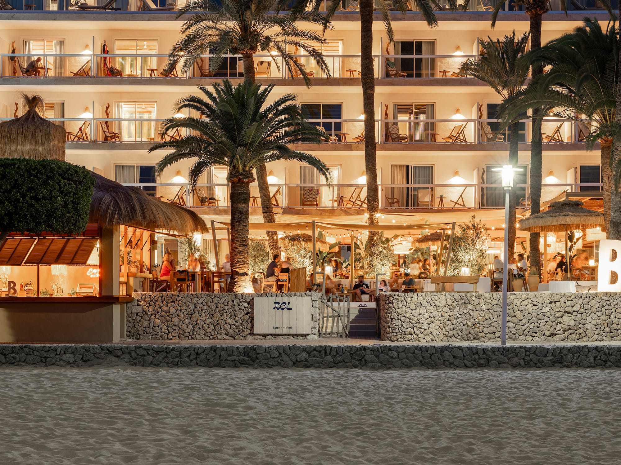 a building with palm trees and people sitting at tables