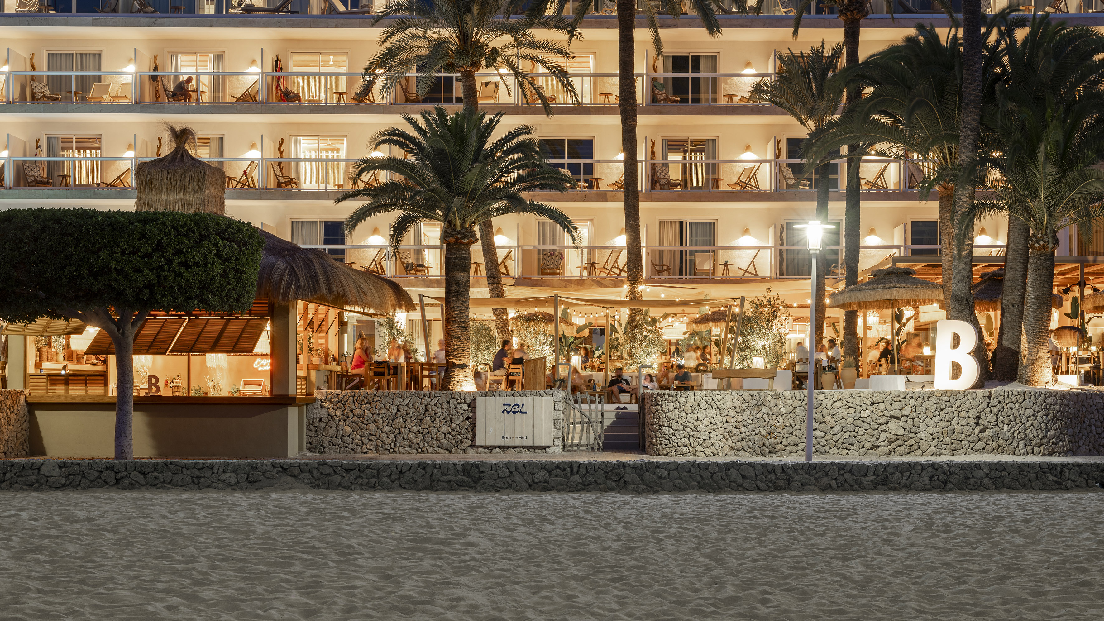 a building with palm trees and people sitting at tables