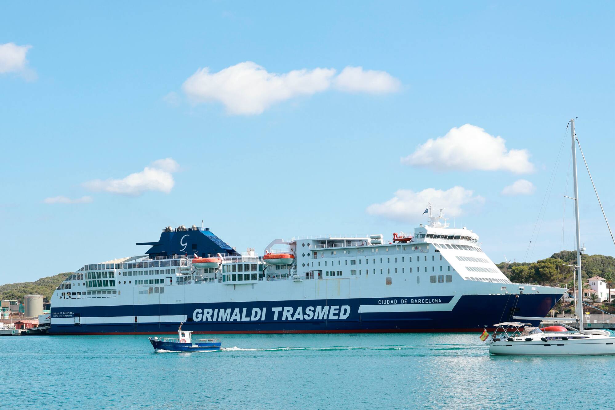 Grimaldi Trasmed ferry Ciudad de Barcelona and boats in a sunny harbor.