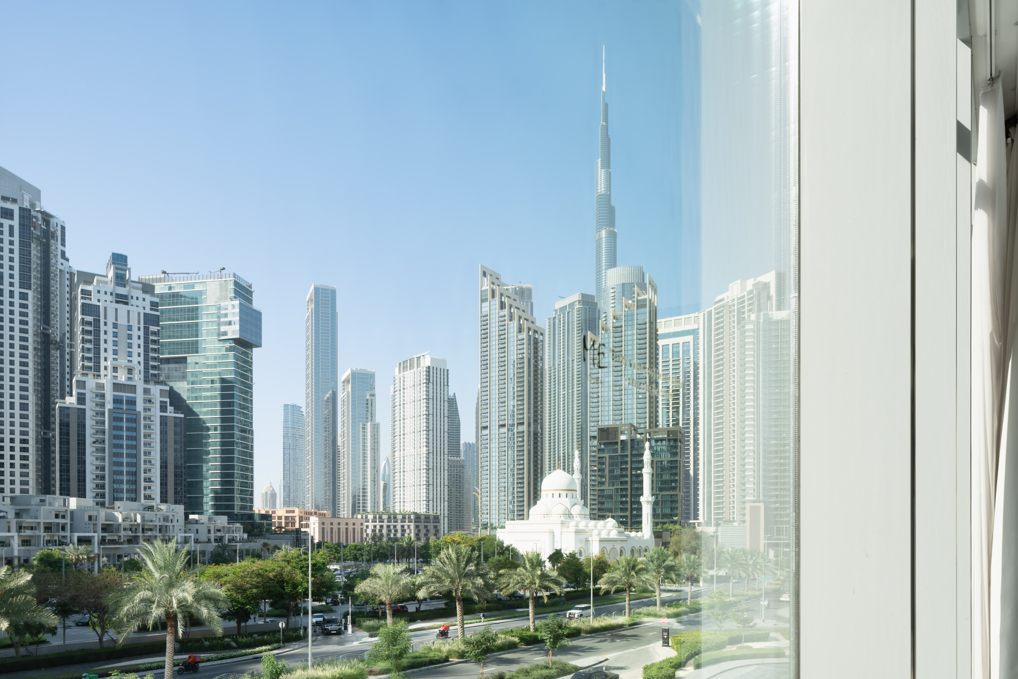 Dubai cityscape with Burj Khalifa, mosque, skyscrapers, and palm trees.