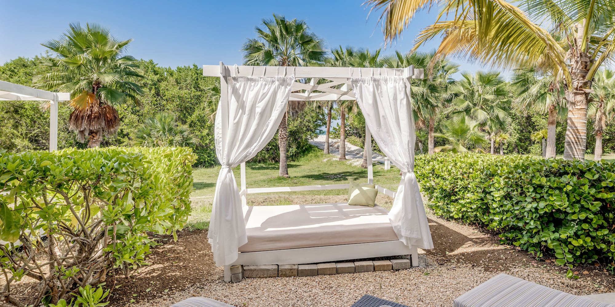 a bed with white curtains and a table in a garden