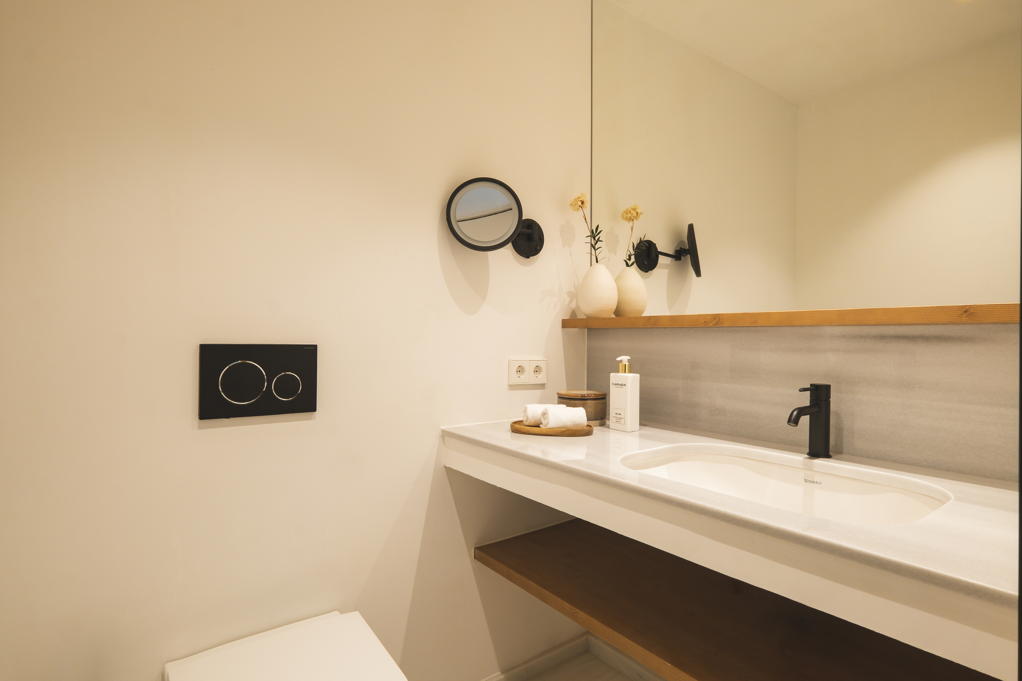 Clean modern bathroom vanity with white sink, black faucet, and marble countertop.