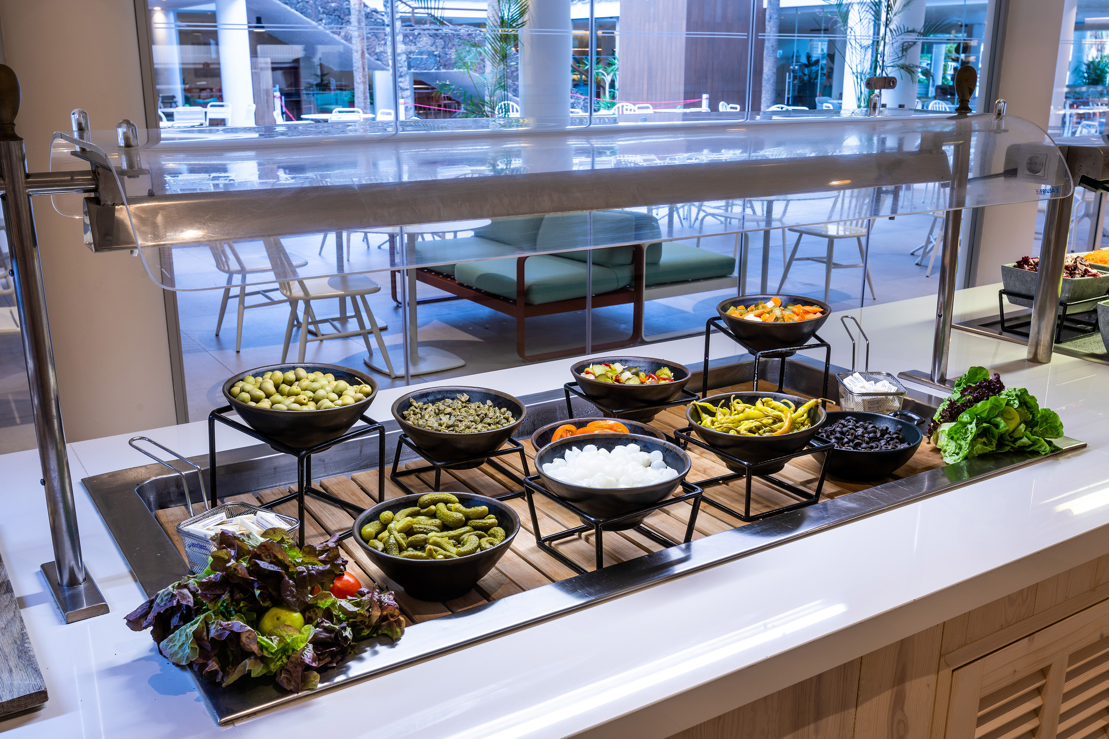 Hotel salad buffet with olives, pickles, peppers, and fresh greens.