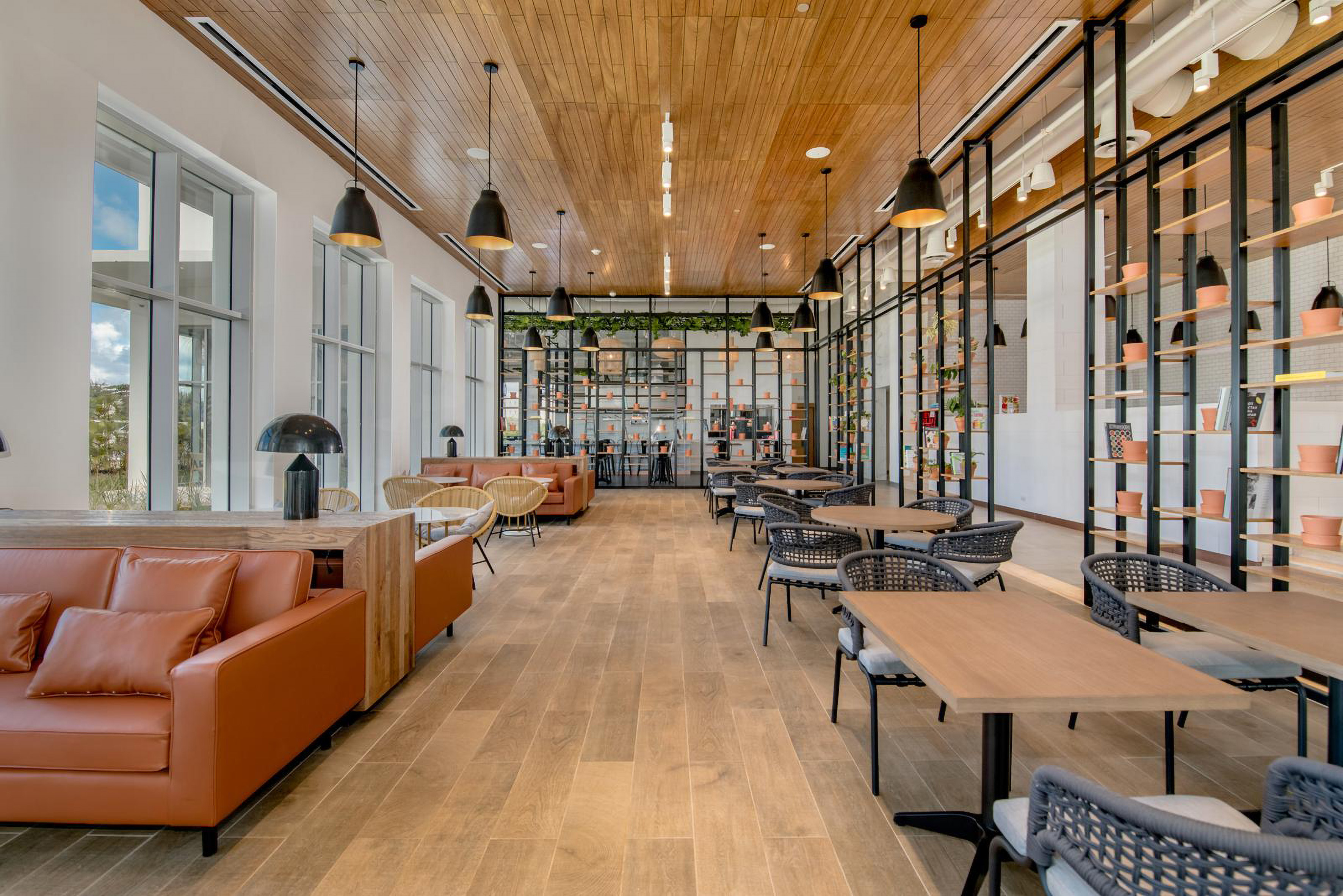 Modern cafe lounge with wood ceiling, sofas, tables, and large windows.