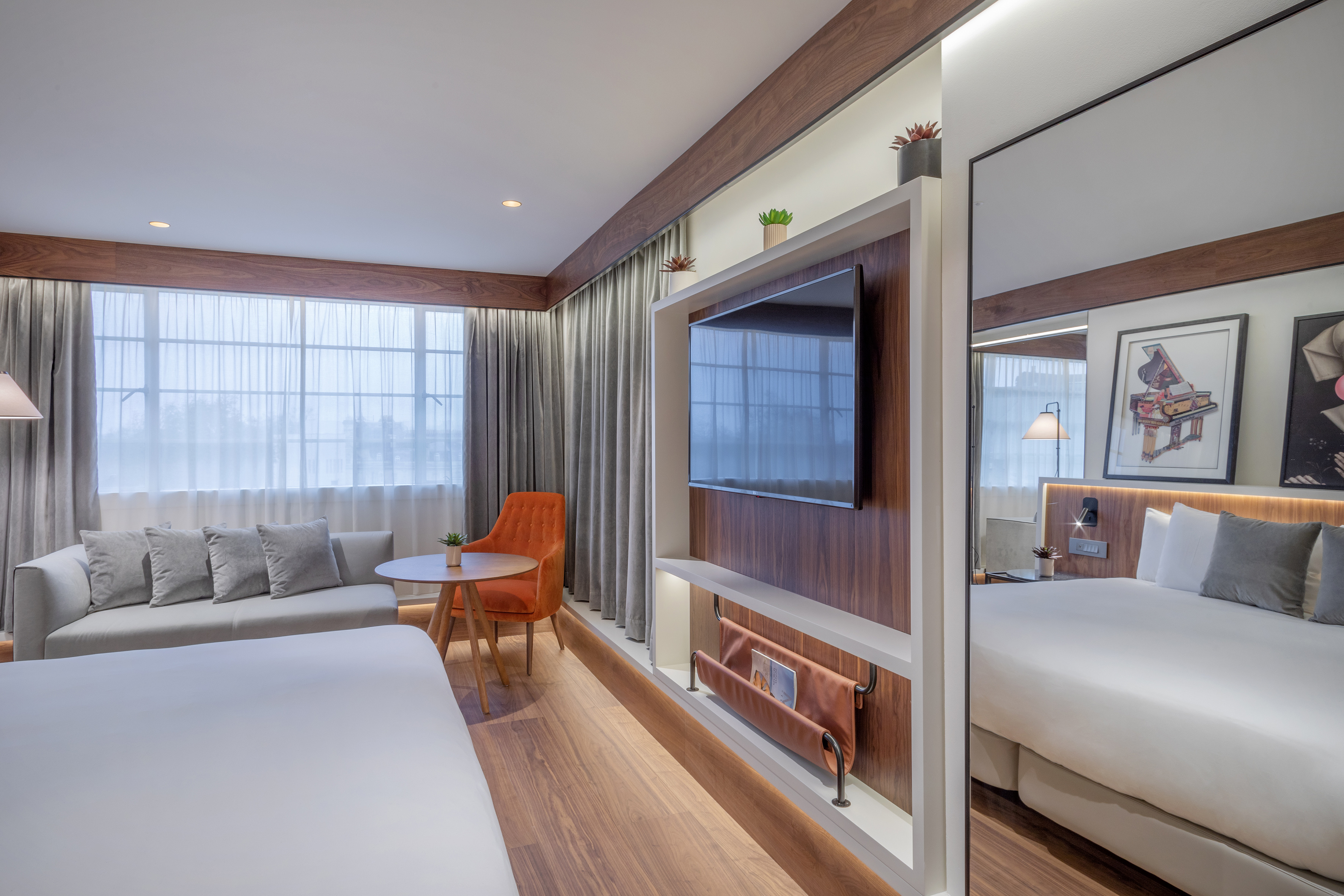 Modern hotel room with sofa, wall TV, and bed. Contemporary living-sleeping space.