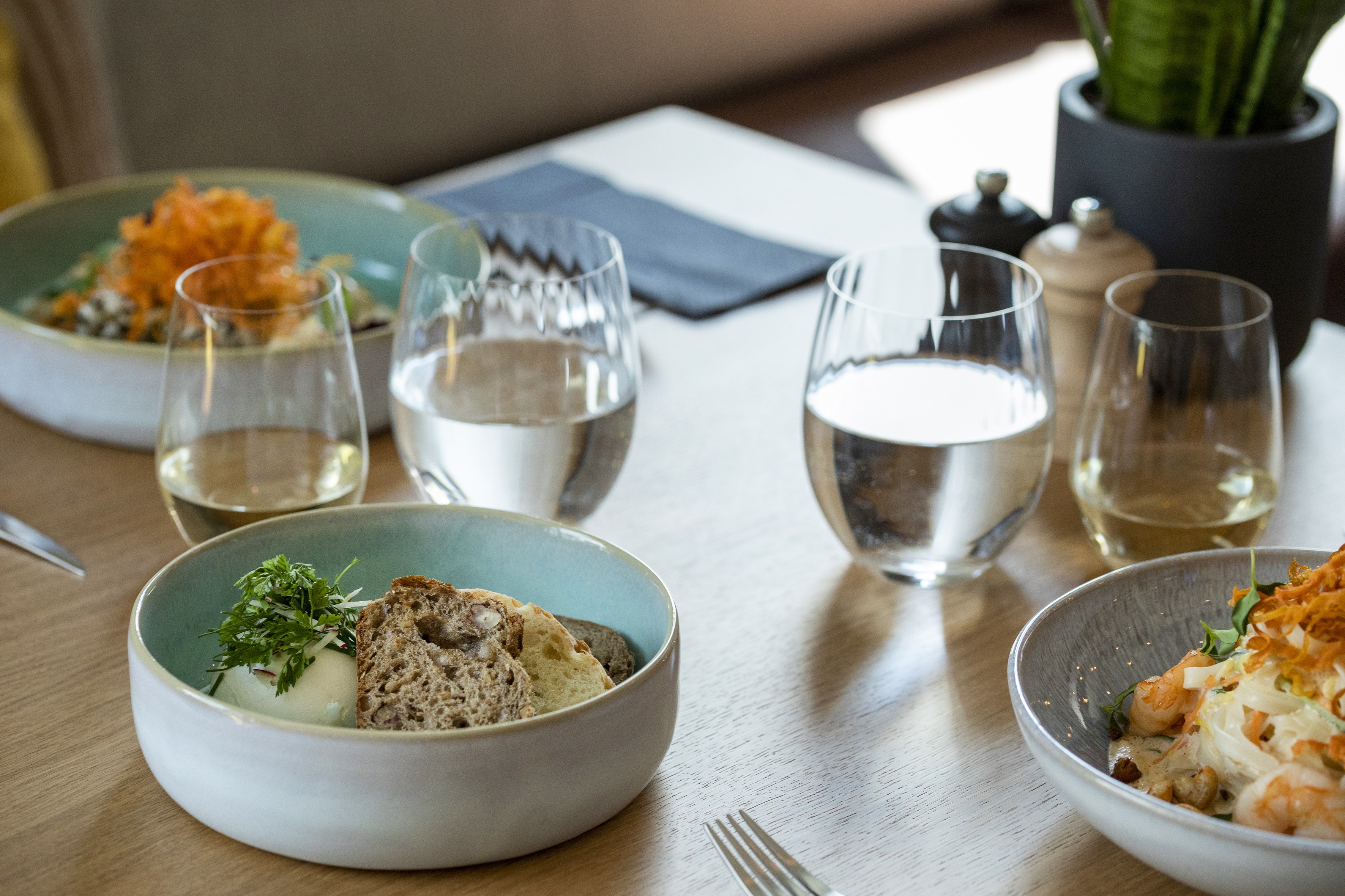 Restaurant table with multiple healthy dishes, wine, and water glasses. - De Gaart, Cuisine locale - INNSiDE Luxembourg, Luxembourg