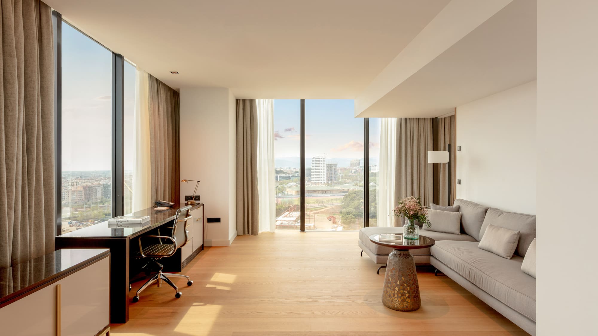 Bright modern suite with panoramic city views, living area, and workspace.