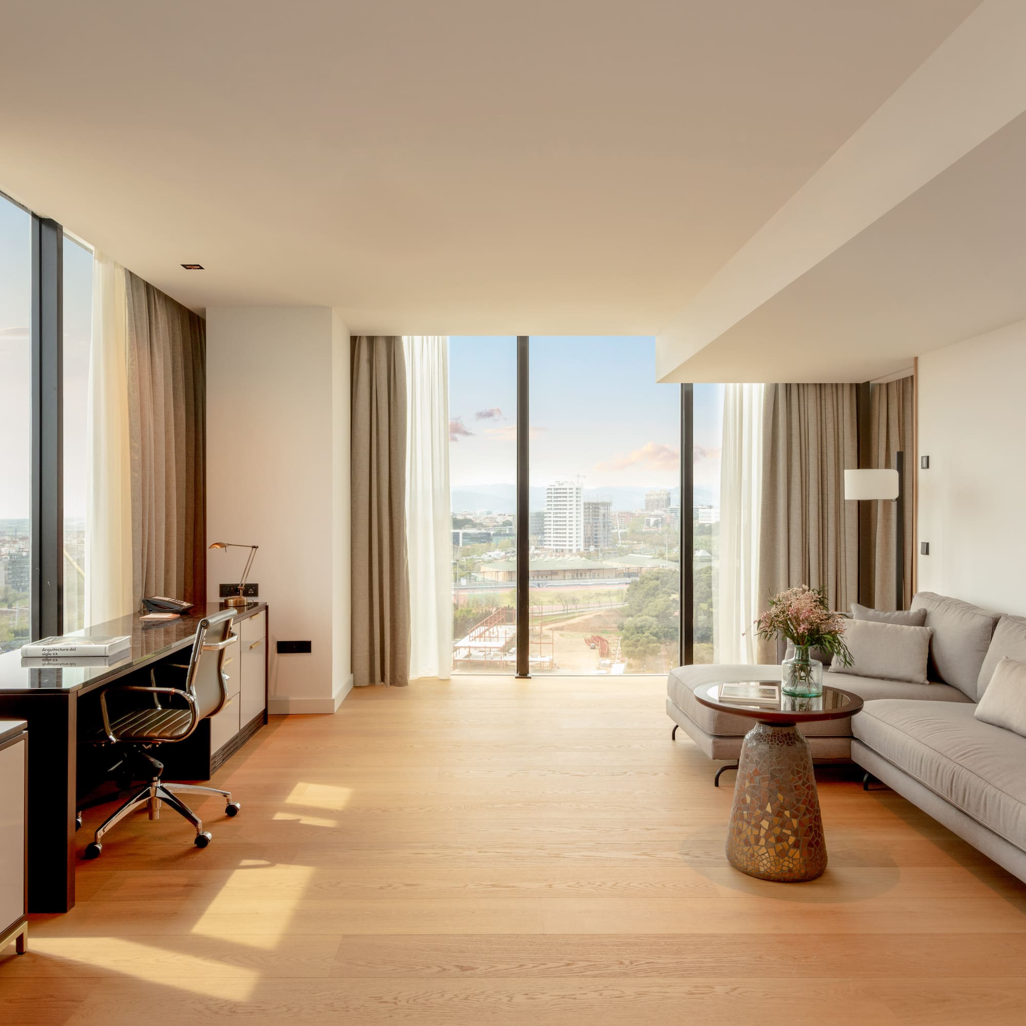 Bright modern suite with panoramic city views, living area, and workspace.