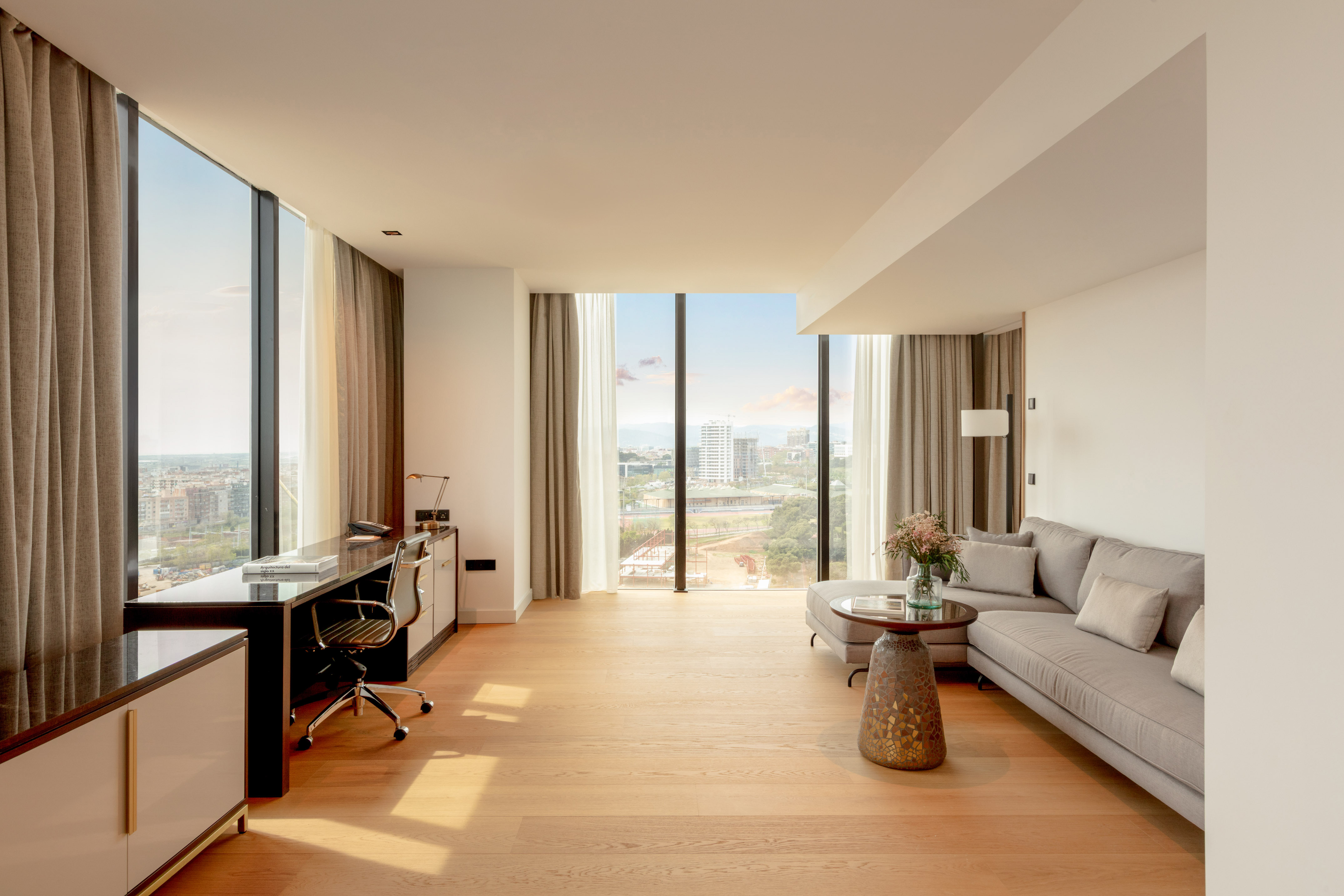 Bright modern suite with panoramic city views, living area, and workspace.