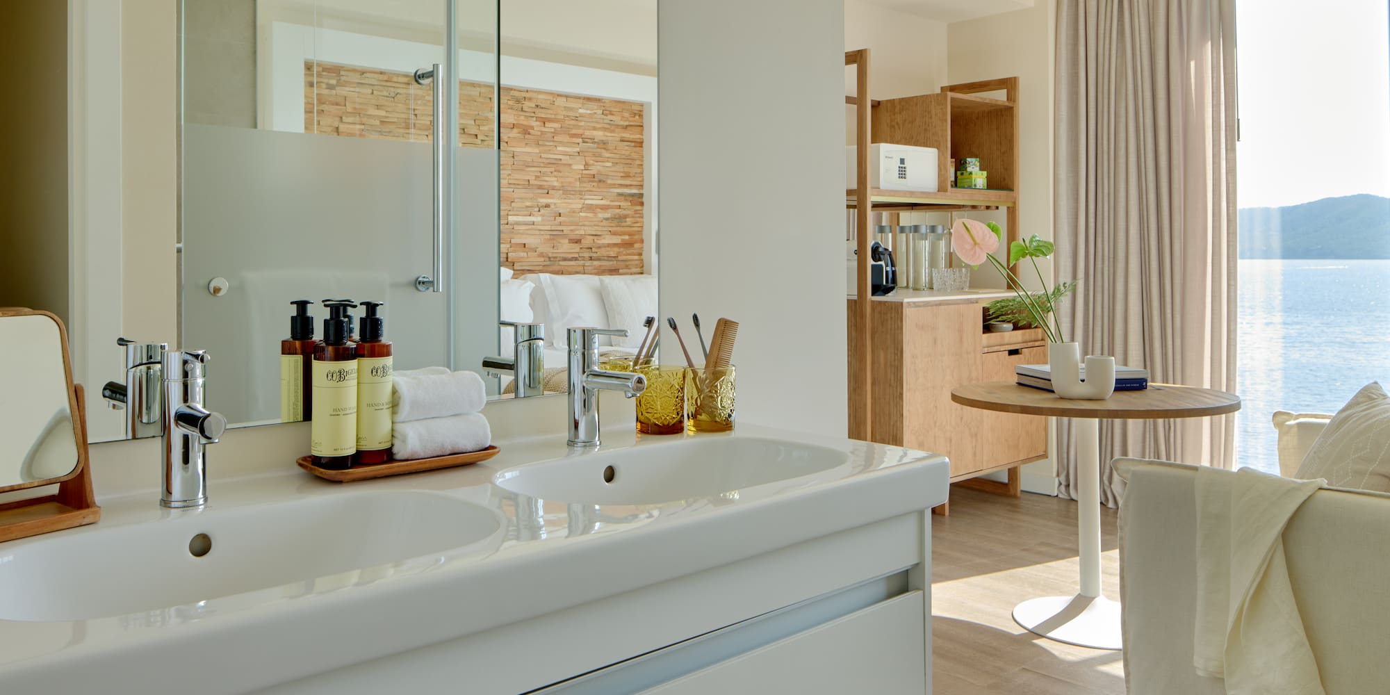 Modern hotel bathroom with double vanity overlooking a sea view suite.
