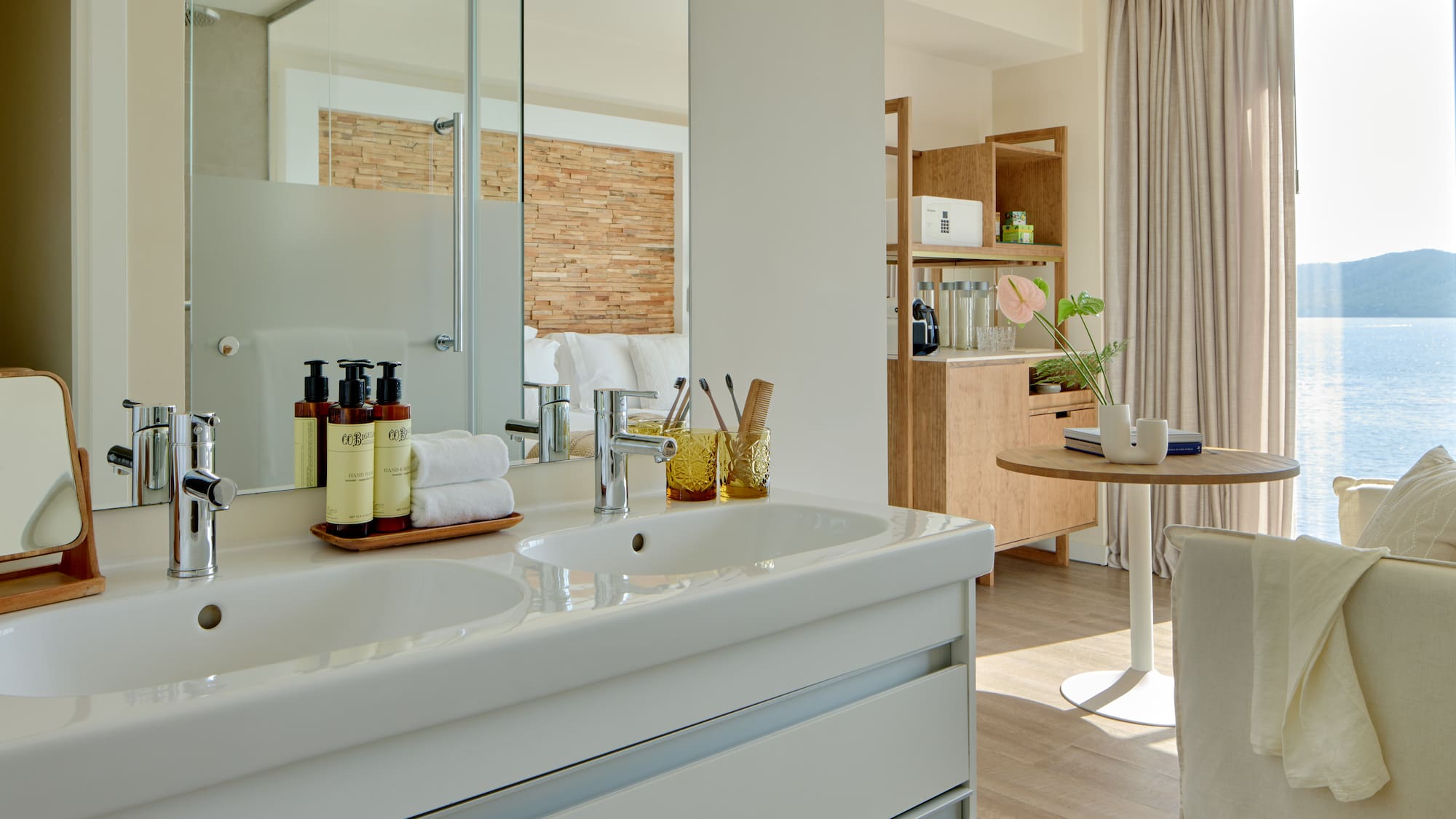 Modern hotel bathroom with double vanity overlooking a sea view suite.