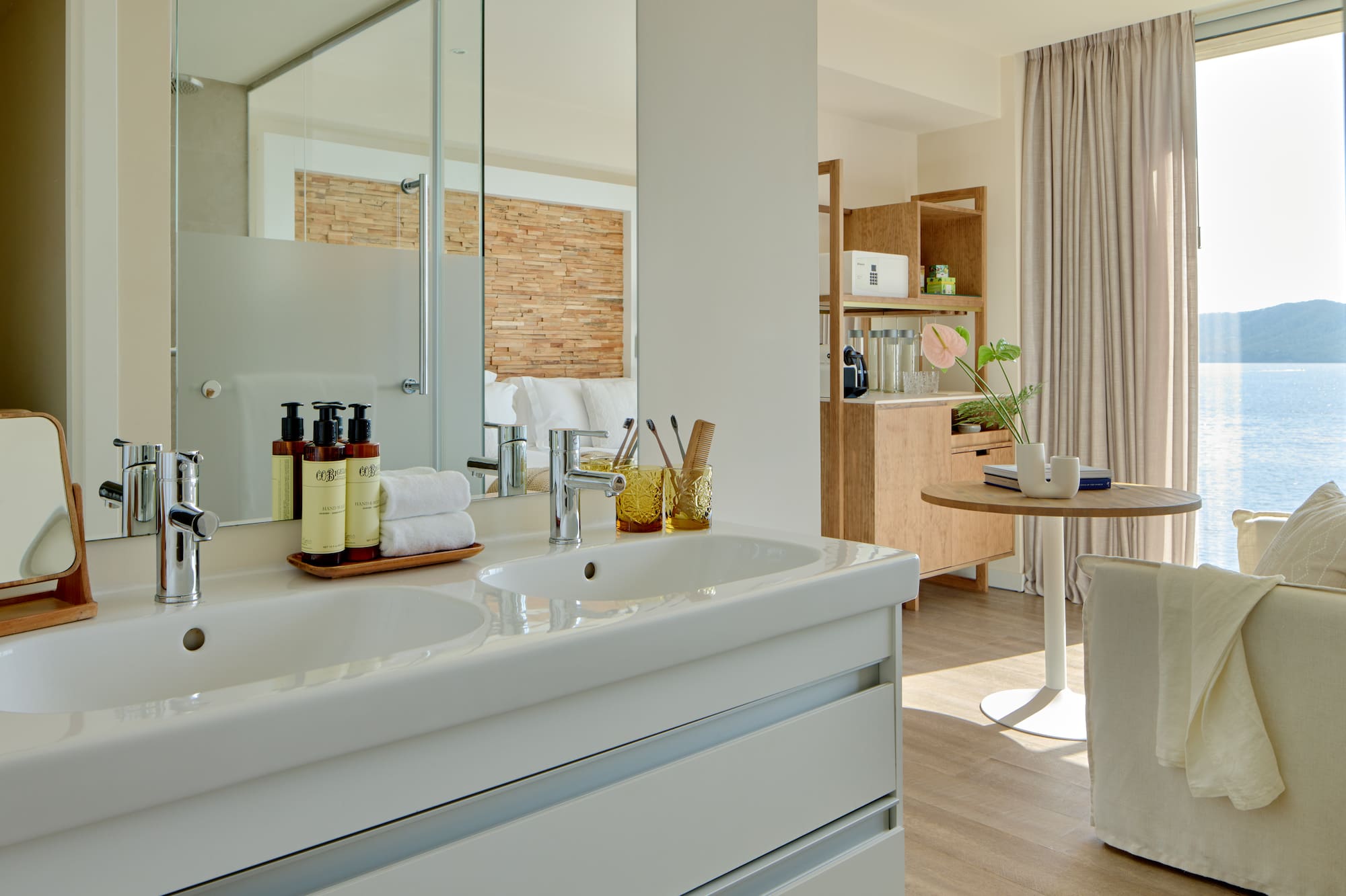 Modern hotel bathroom with double vanity overlooking a sea view suite.