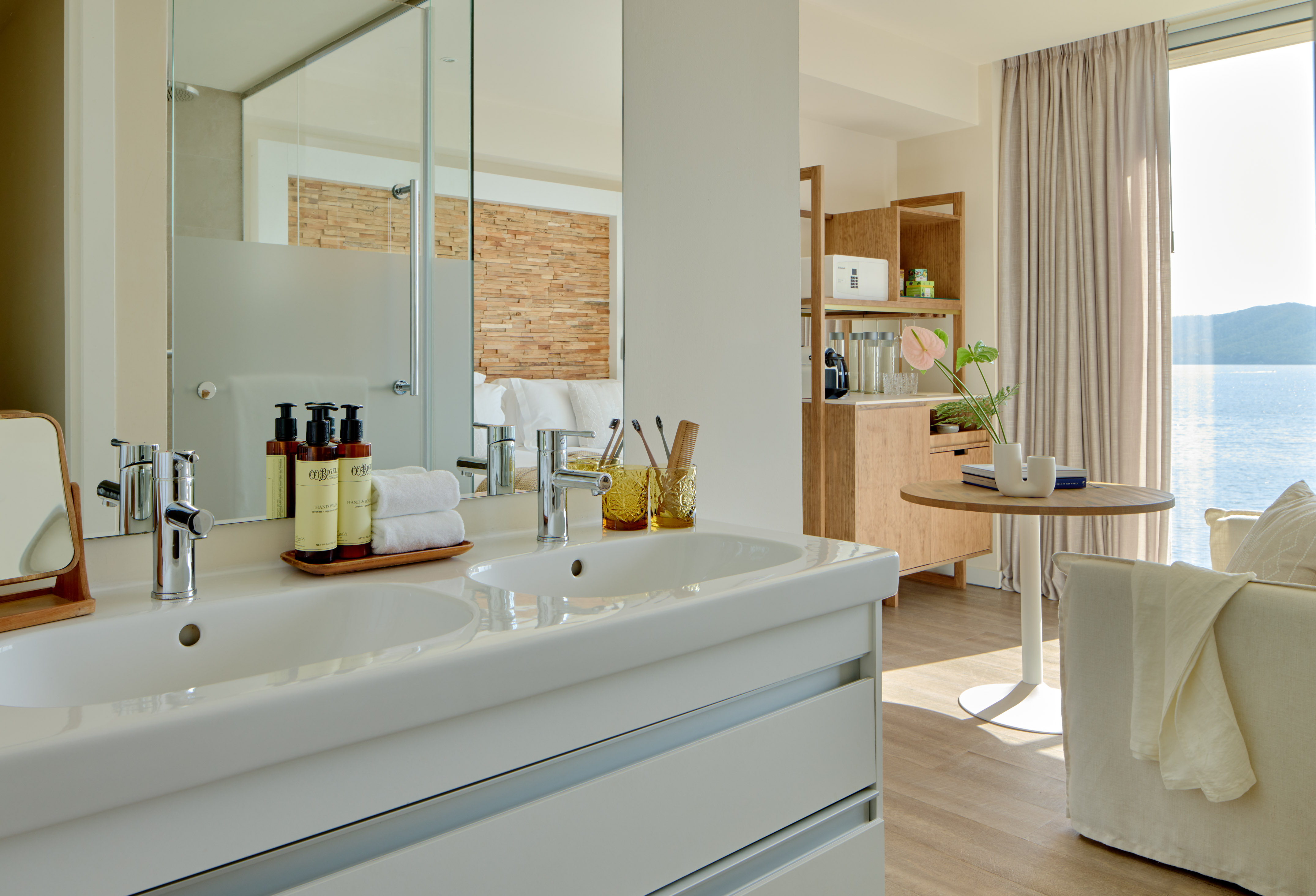 Modern hotel bathroom with double vanity overlooking a sea view suite.