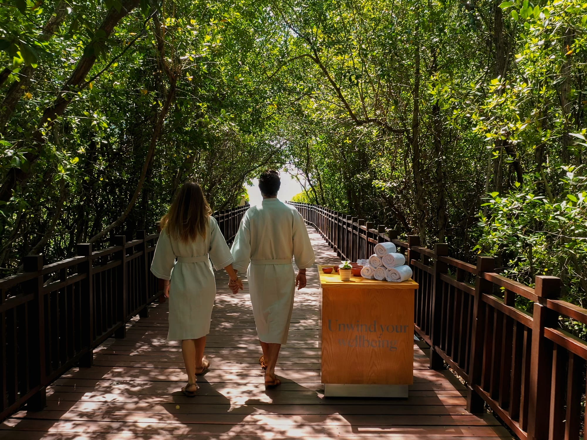 a man and woman walking on a bridge with a cart of towels
