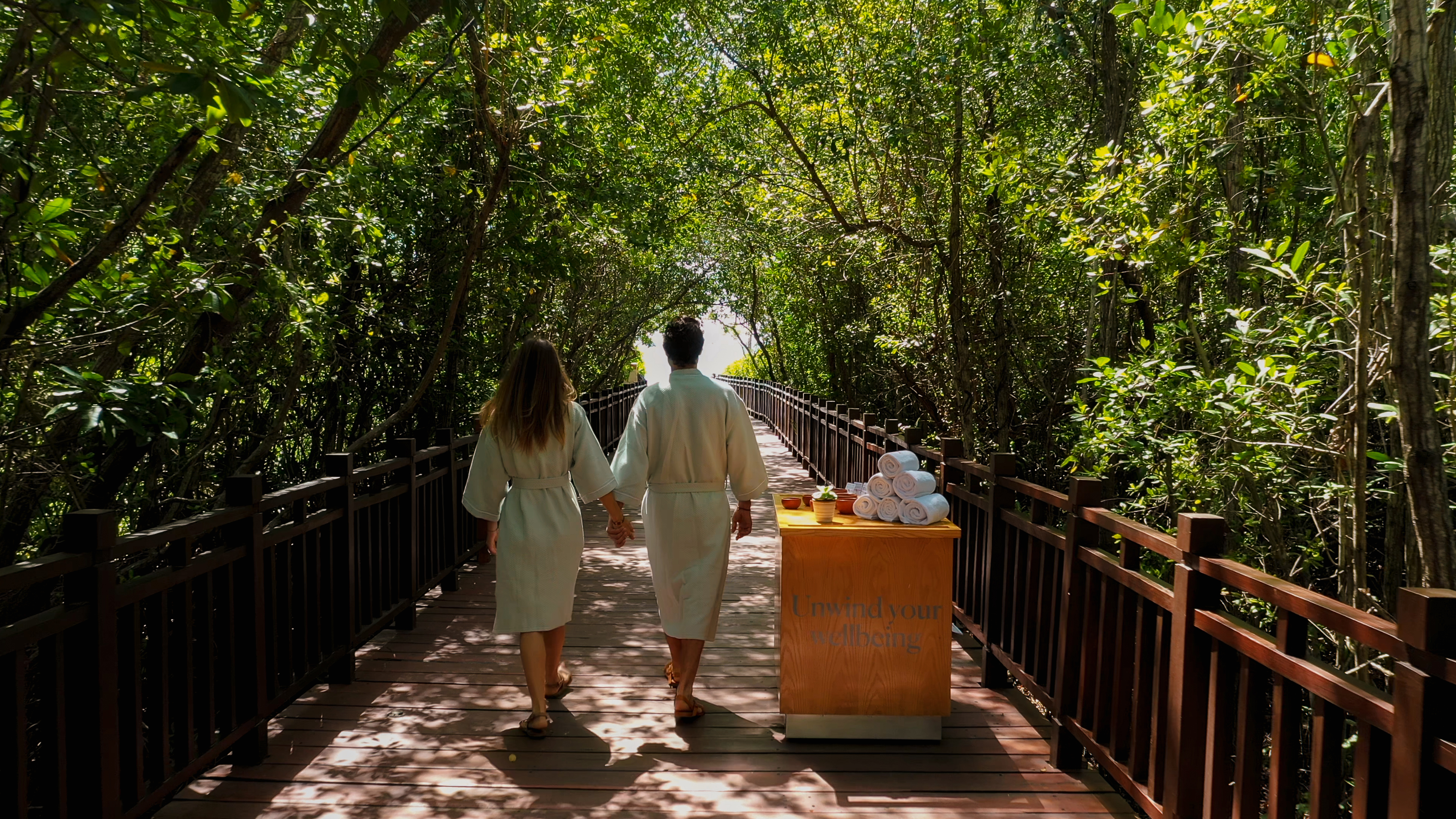a man and woman walking on a bridge with a cart of towels