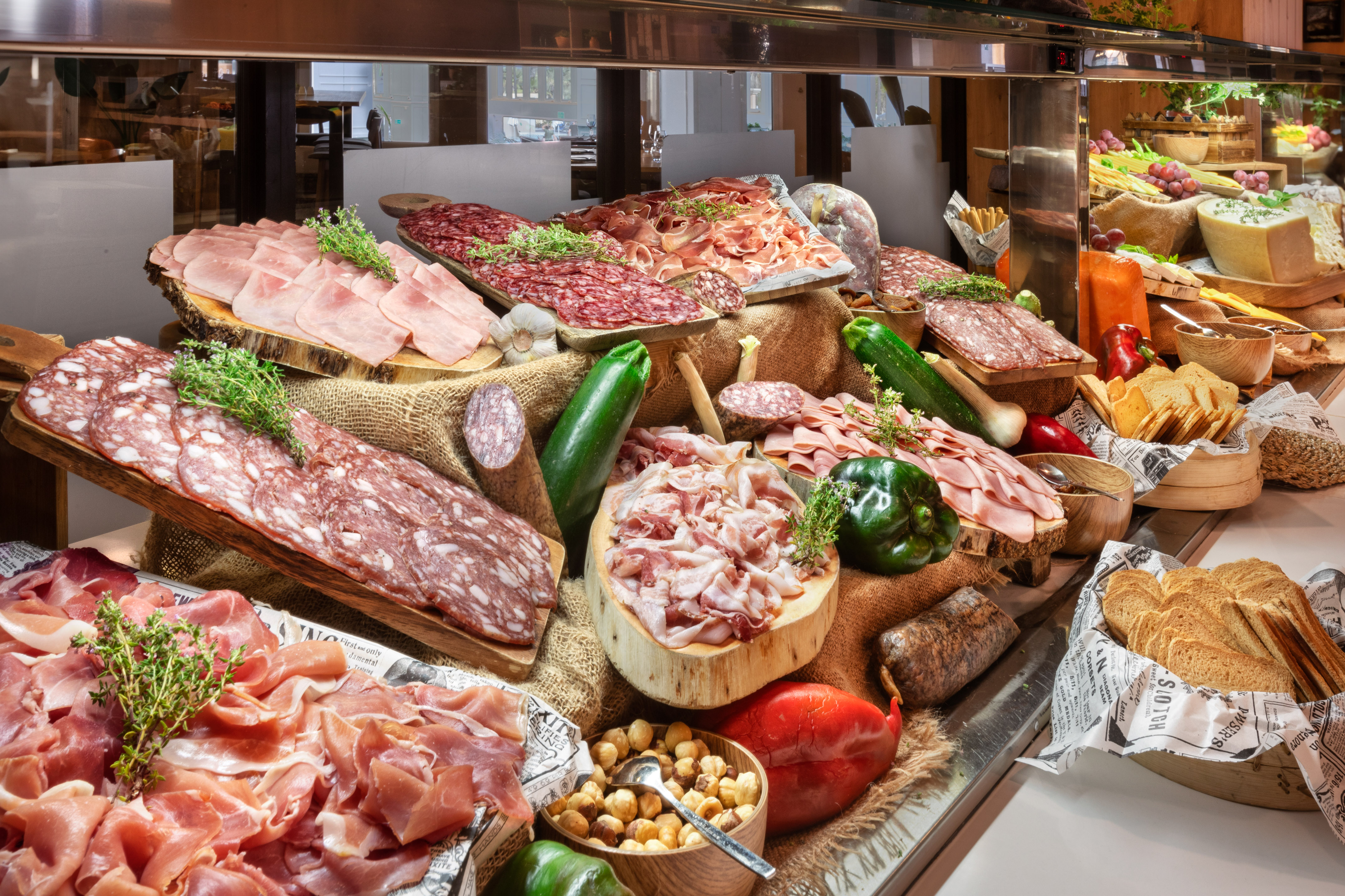 Extensive charcuterie buffet with ham, salami, prosciutto, cheese, bread, vegetables.