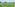 Green artificial turf soccer field with white lines, floodlights, and sea view.