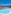 Resort swimming pool, blue sea, mountains, palm trees, lounge chairs.