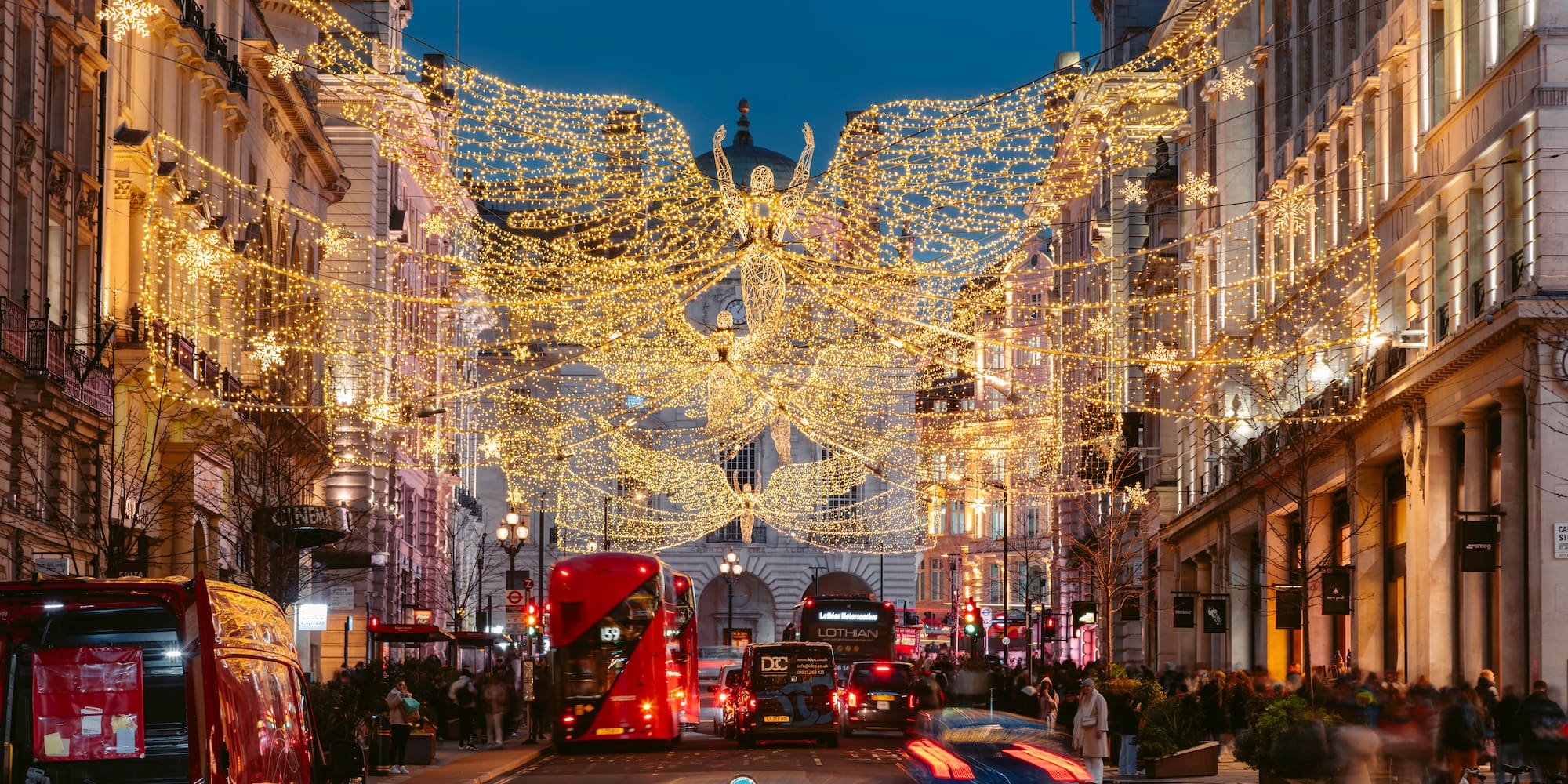 Luces navideñas de ángeles en Regent Street, Londres, con tráfico.
