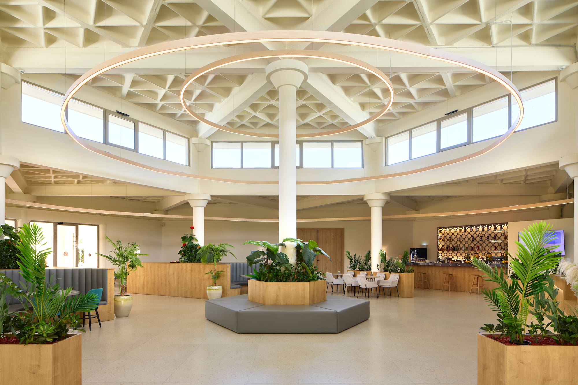 Spacious, modern hotel lobby featuring circular lights, plants, and lounge seating.