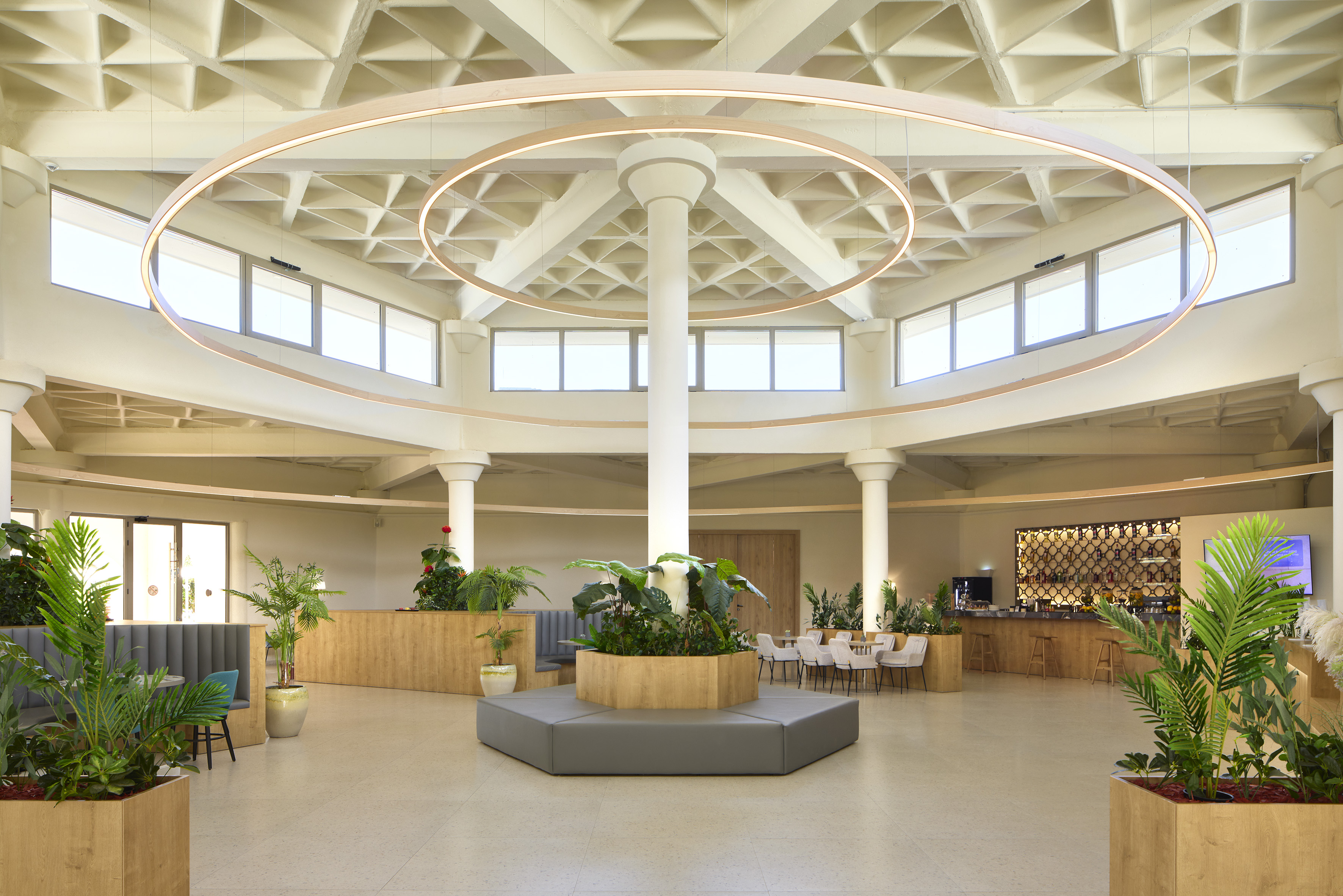 Spacious, modern hotel lobby featuring circular lights, plants, and lounge seating.