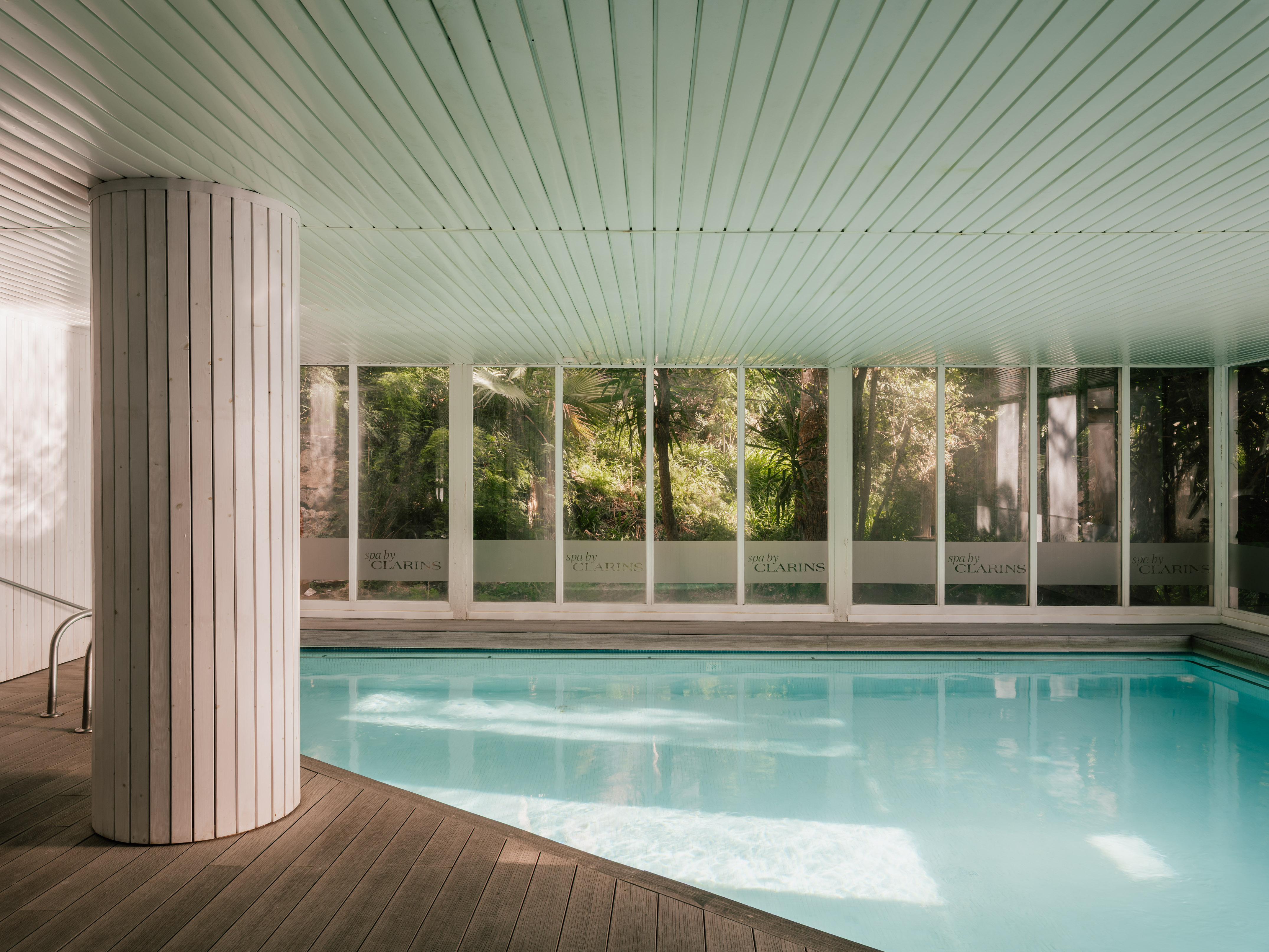 Indoor Clarins spa pool with wooden deck and nature views.