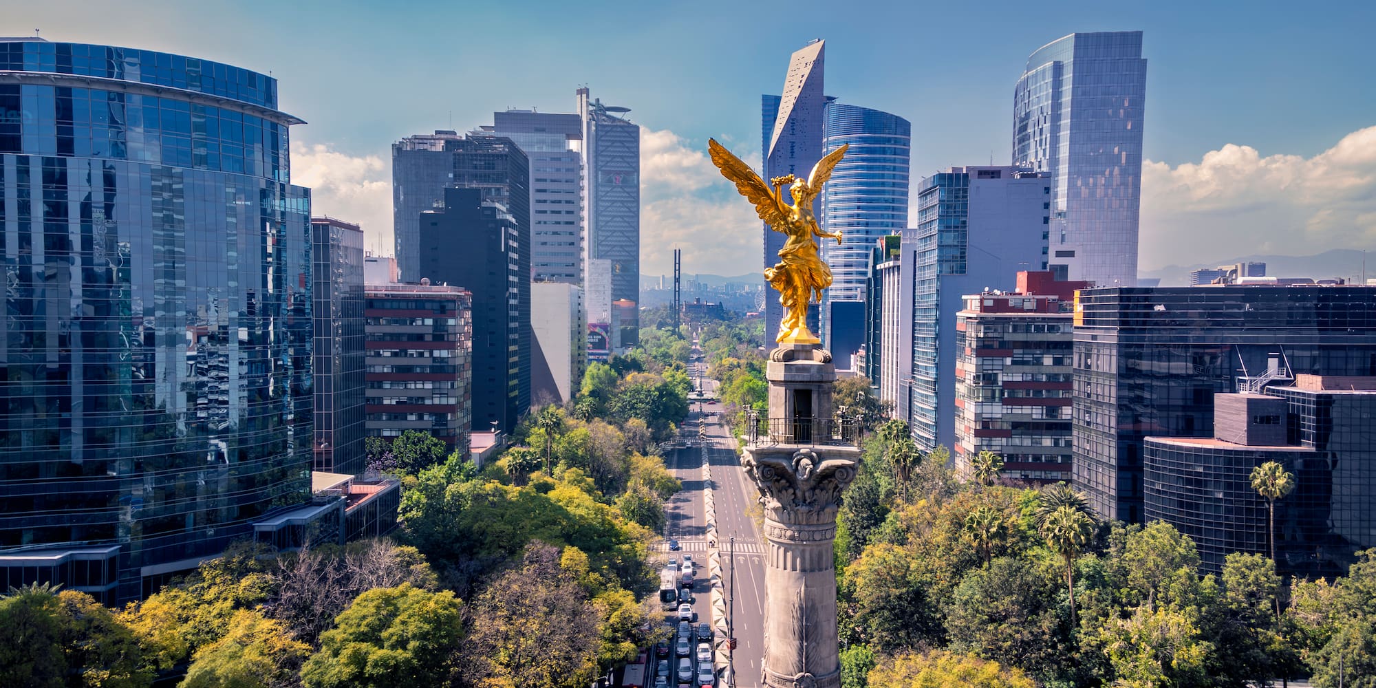 Golden Angel monument on Reforma boulevard with Mexico City's modern skyline.