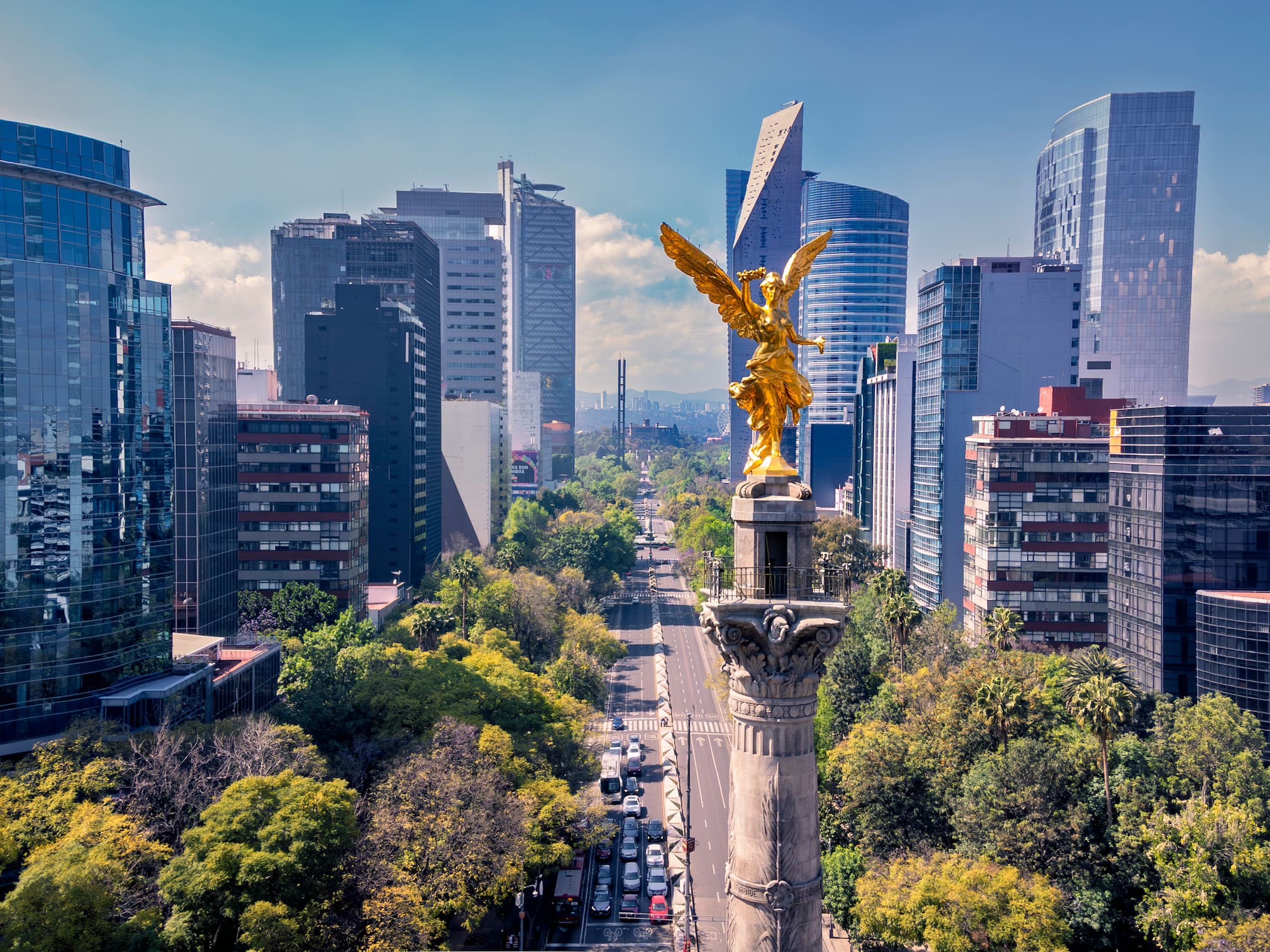 Golden Angel monument on Reforma boulevard with Mexico City's modern skyline.