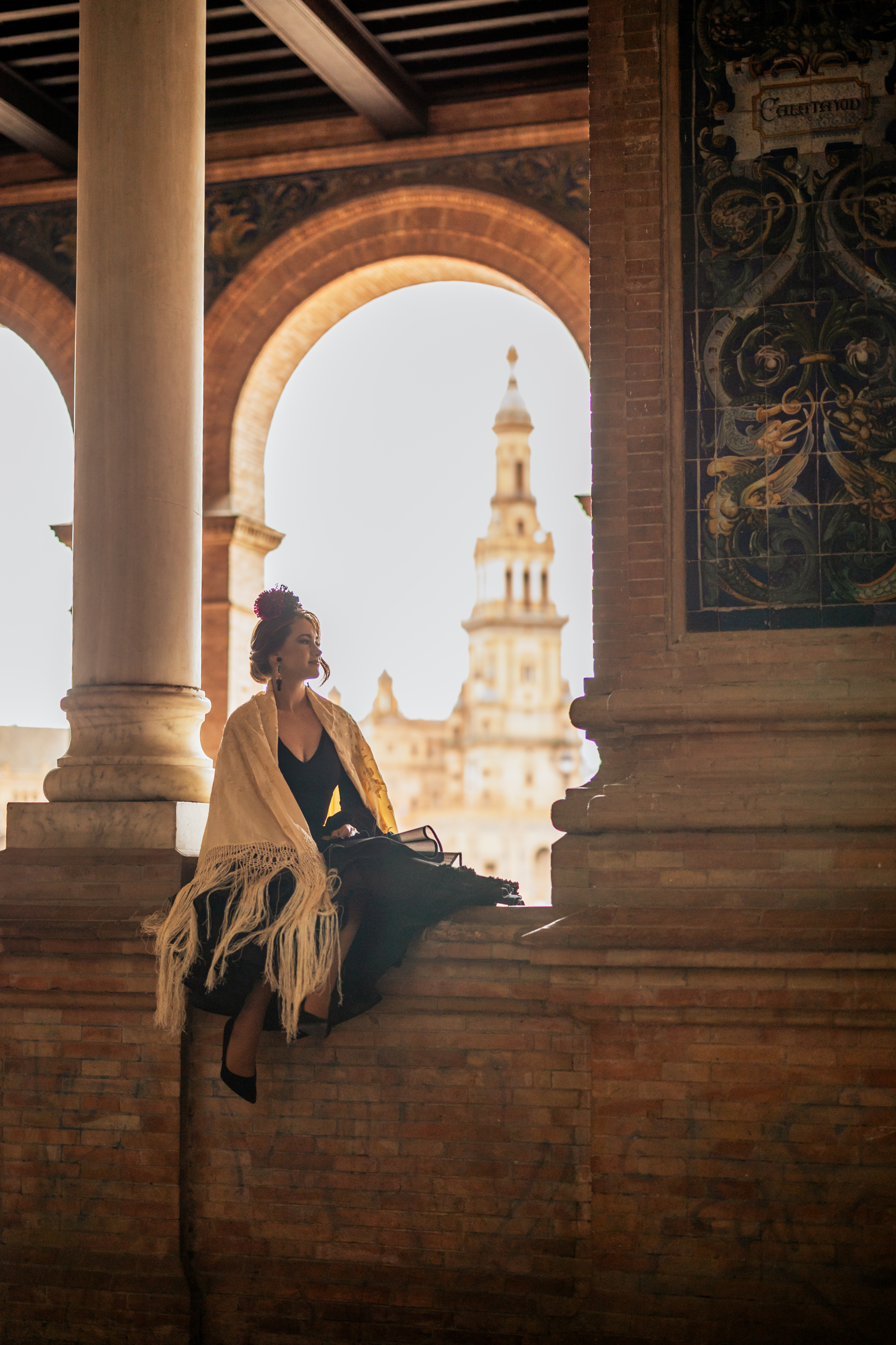 Woman in traditional Spanish shawl sitting at Plaza de España, Seville.