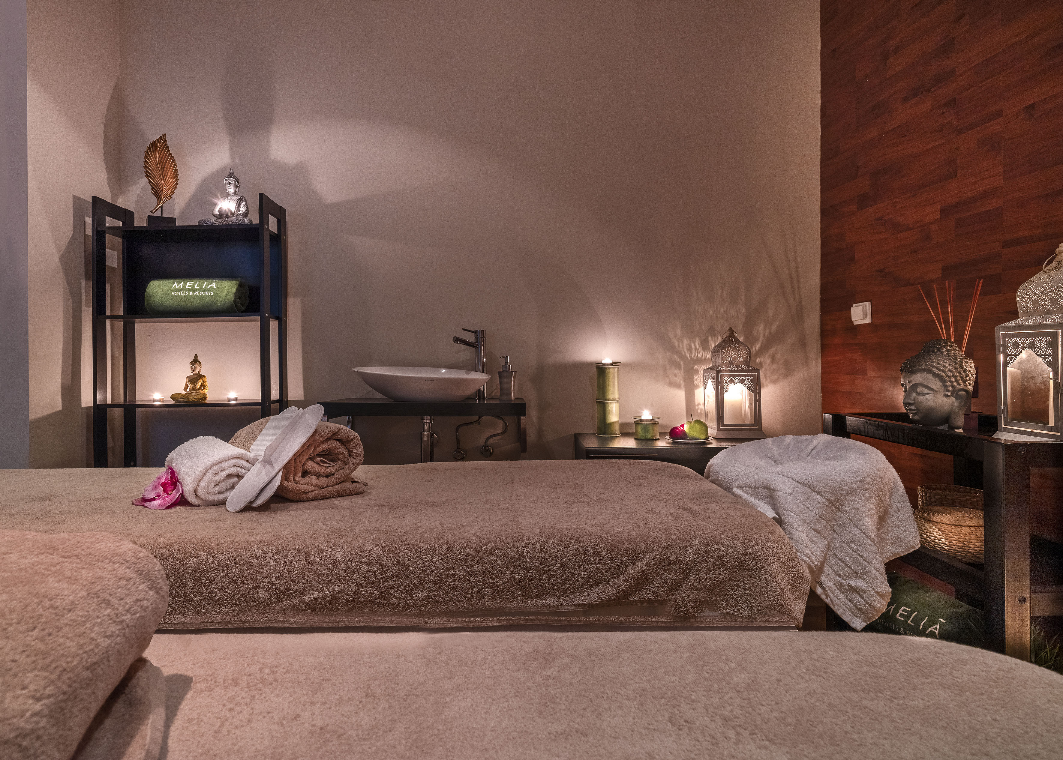 Meliá spa treatment room with massage bed, Buddha decor, and soft lighting.