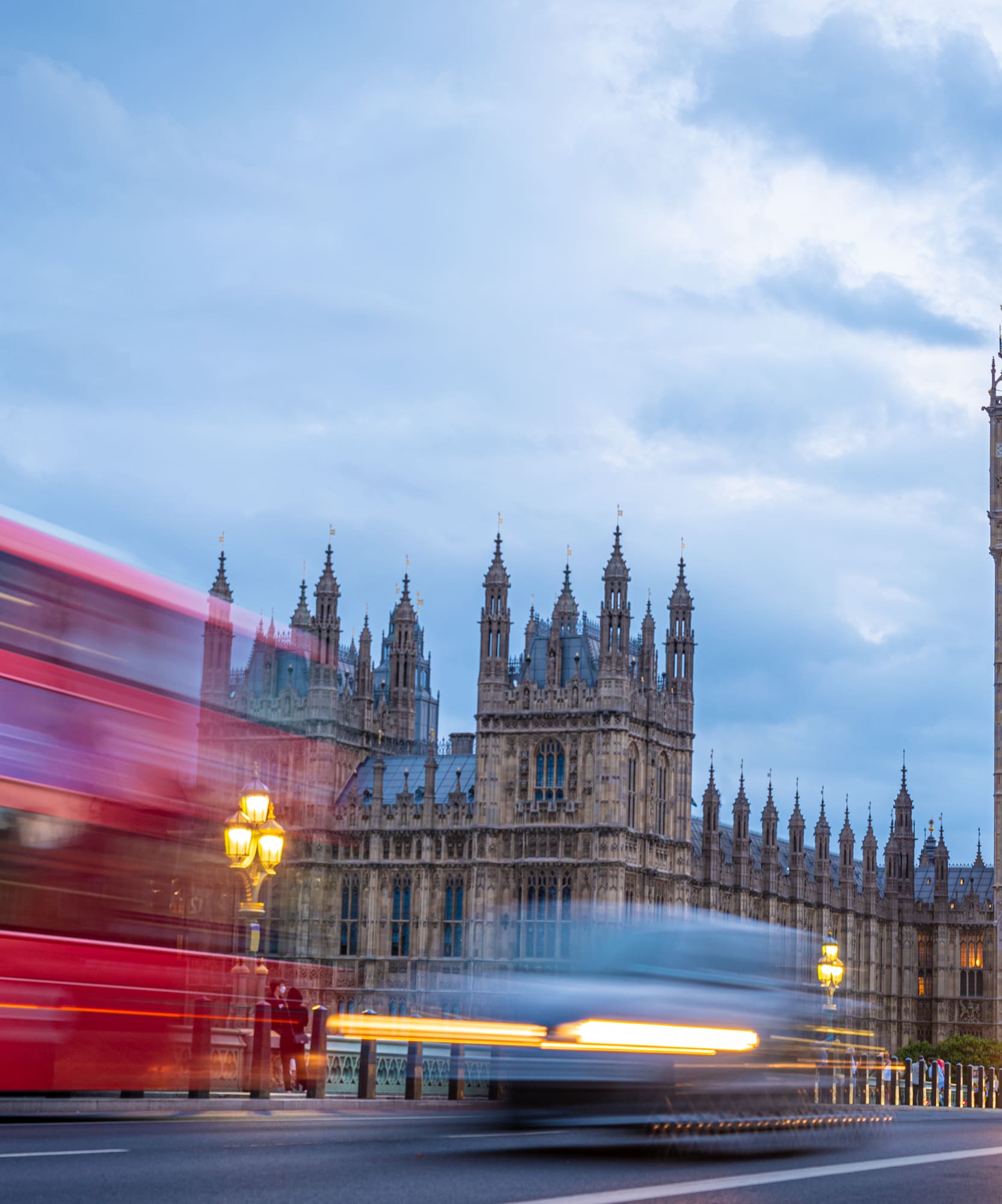 Big Ben y Parlamento de Londres al atardecer con autobuses rojos en movimiento.