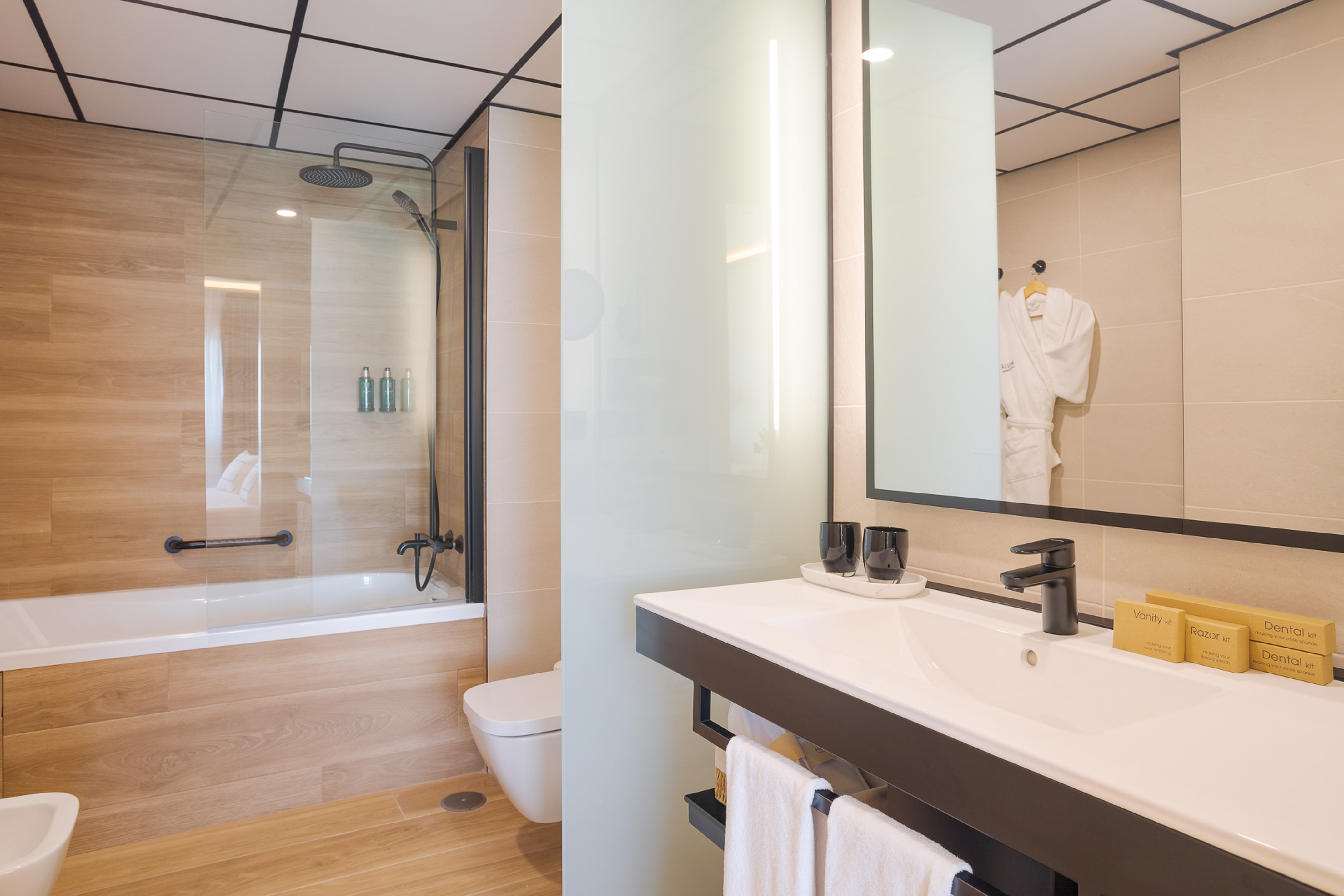 Modern hotel bathroom with shower, bathtub, vanity, and essential amenities.