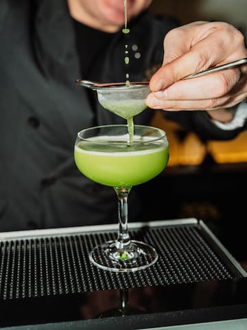 a person pouring a drink into a glass