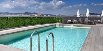 a swimming pool with chairs and a building in the background