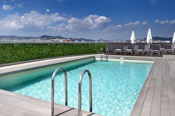 a swimming pool with chairs and a building in the background