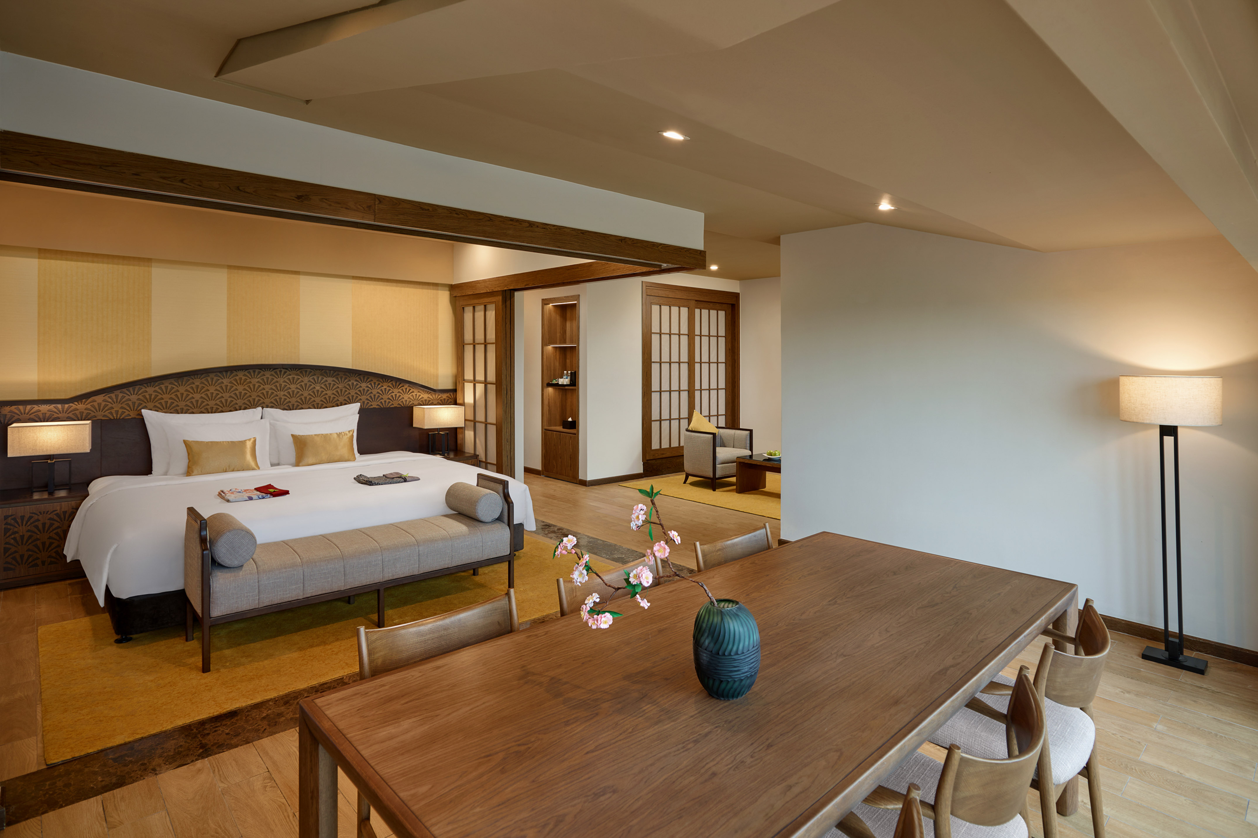 Luxury hotel suite: bedroom with king bed, dining table, and seating area.