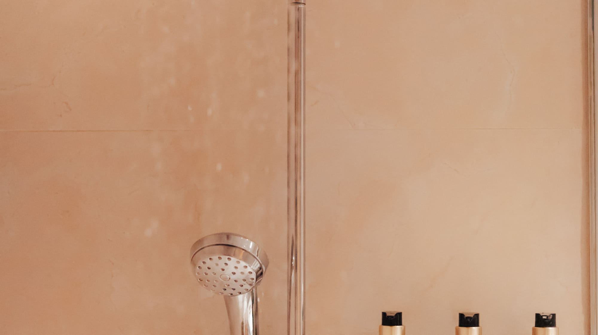 Hotel shower with Rituals of Jing shampoo, shower gel, and conditioner.