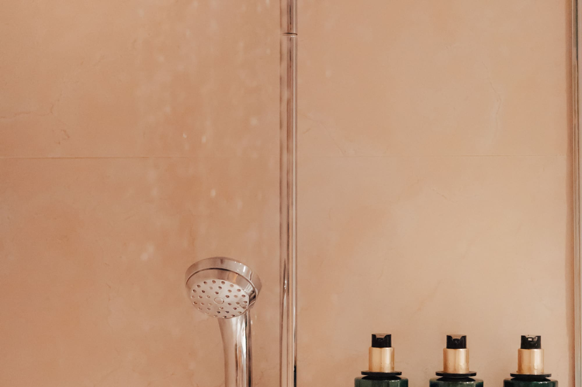 Hotel shower with Rituals of Jing shampoo, shower gel, and conditioner.