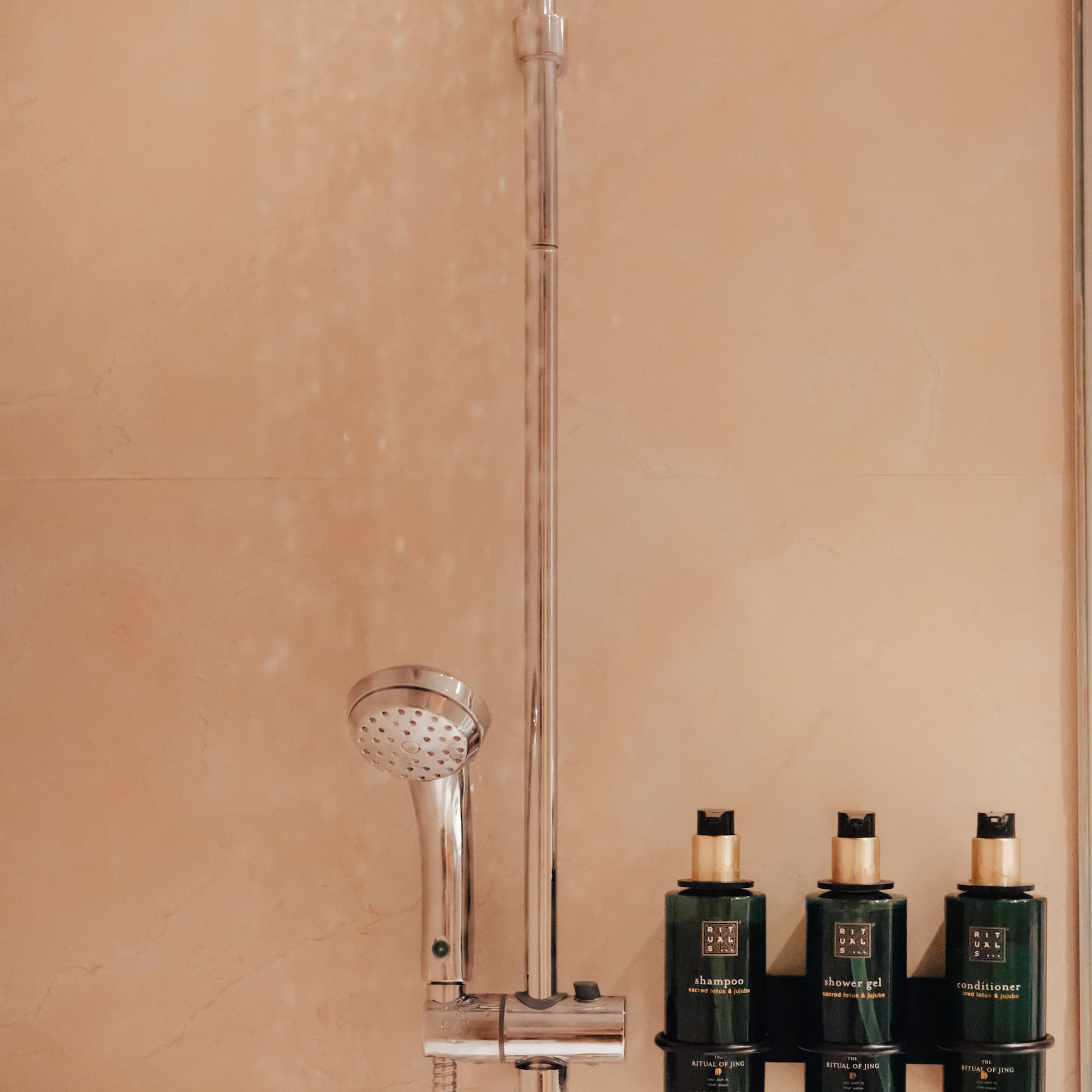 Hotel shower with Rituals of Jing shampoo, shower gel, and conditioner.