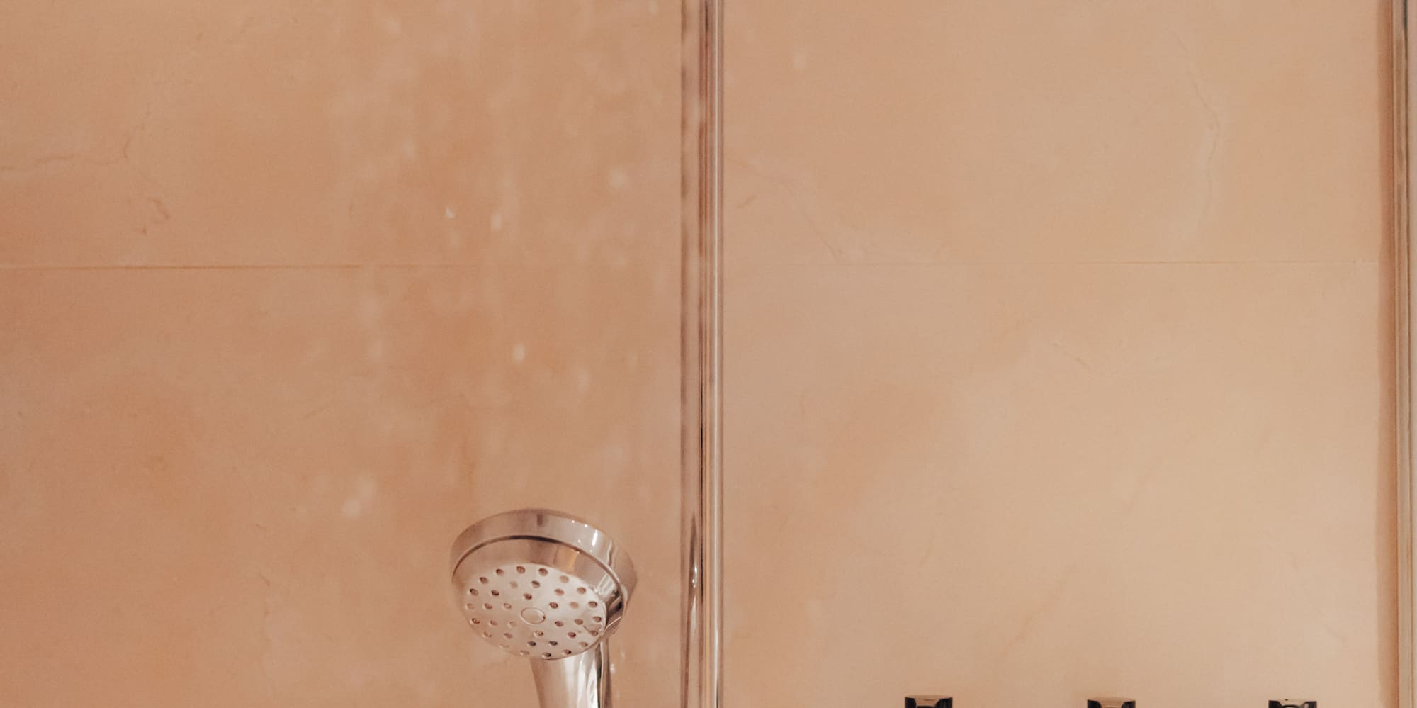 Hotel shower with Rituals of Jing shampoo, shower gel, and conditioner.
